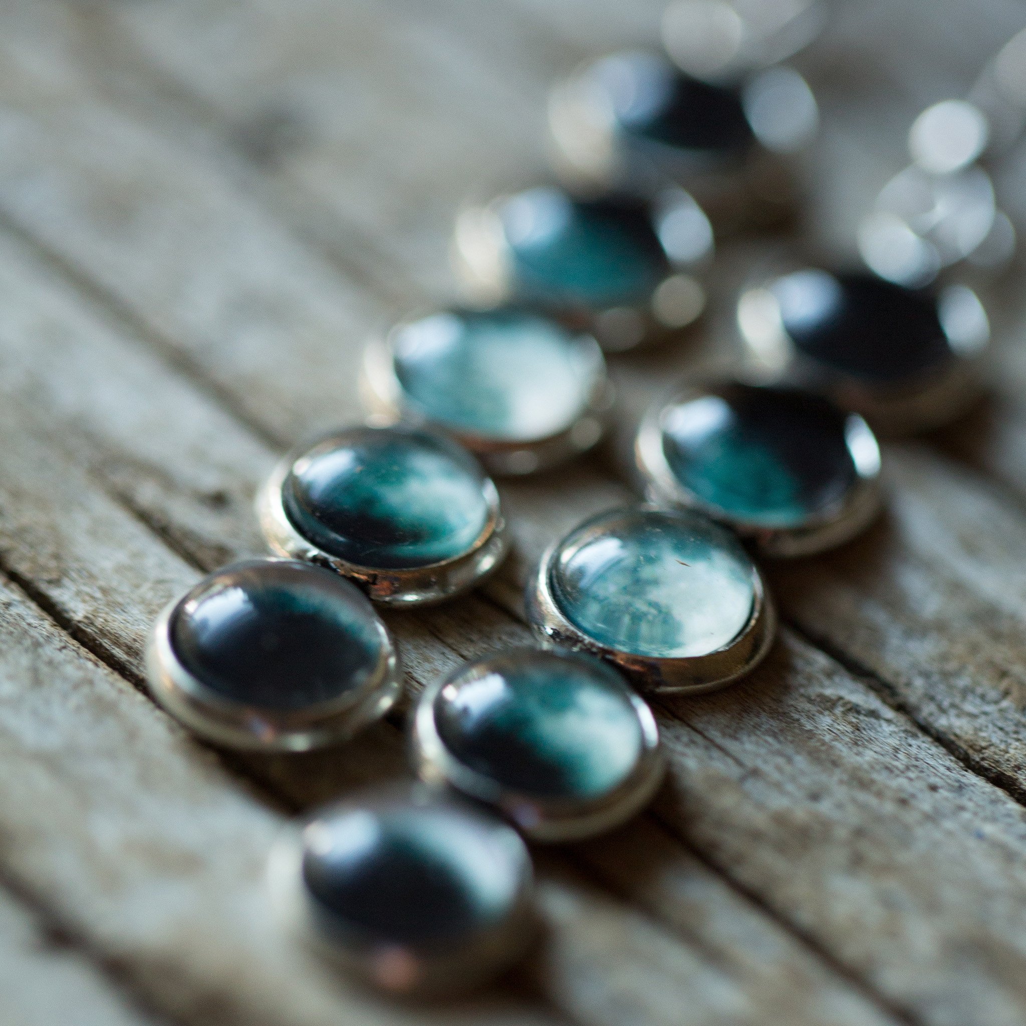 A pair of handcrafted Moon Phase Earrings featuring silver tone bezels and a beautiful representation of the Moon's phases, hanging elegantly from French hooks.