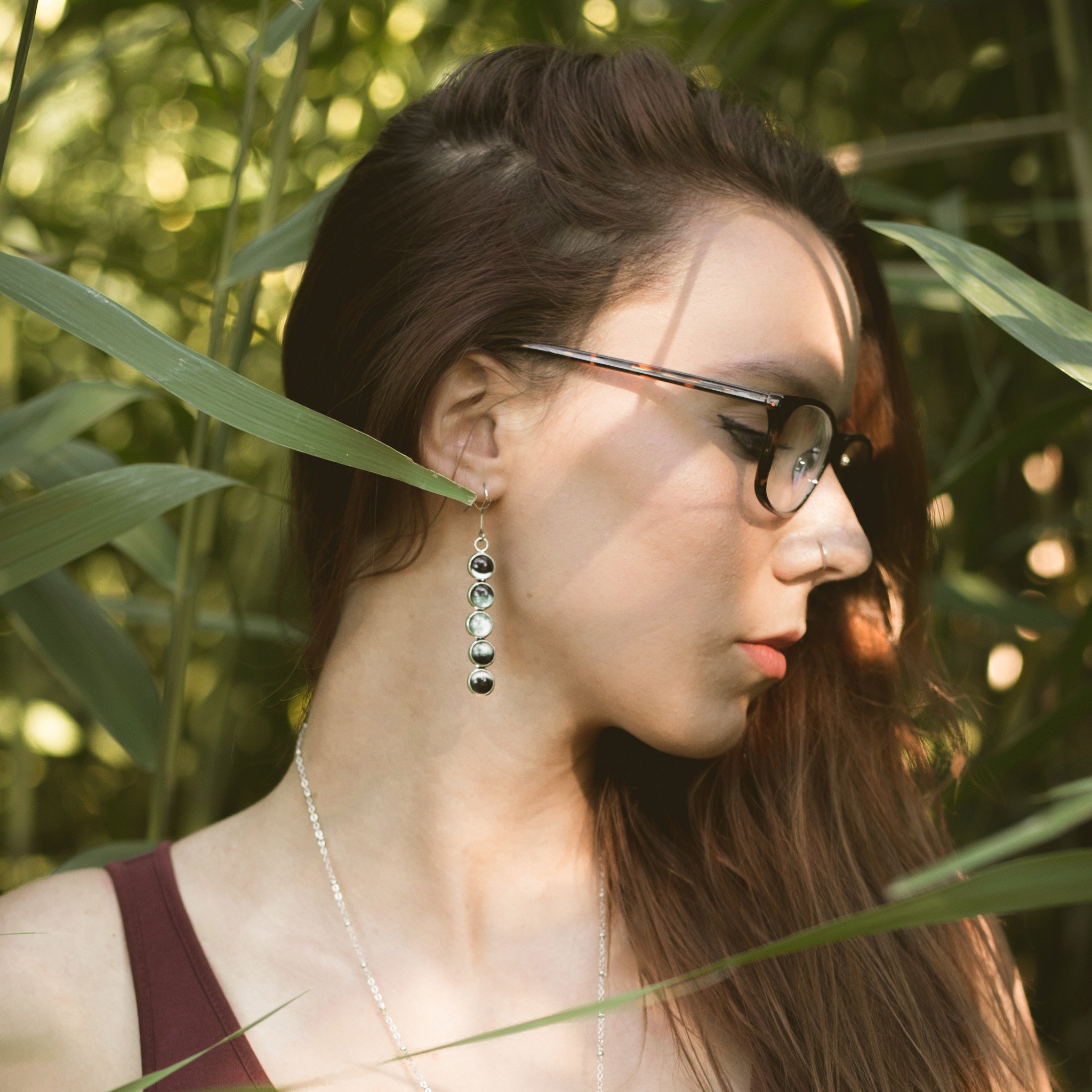 A pair of handcrafted Moon Phase Earrings featuring silver tone bezels and a beautiful representation of the Moon's phases, hanging elegantly from French hooks.