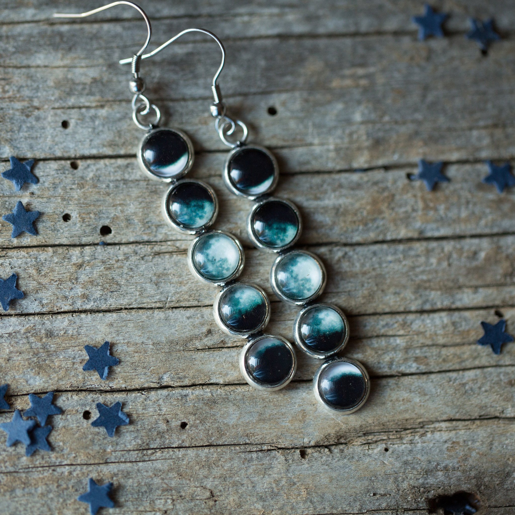 A pair of handcrafted Moon Phase Earrings featuring silver tone bezels and a beautiful representation of the Moon's phases, hanging elegantly from French hooks.