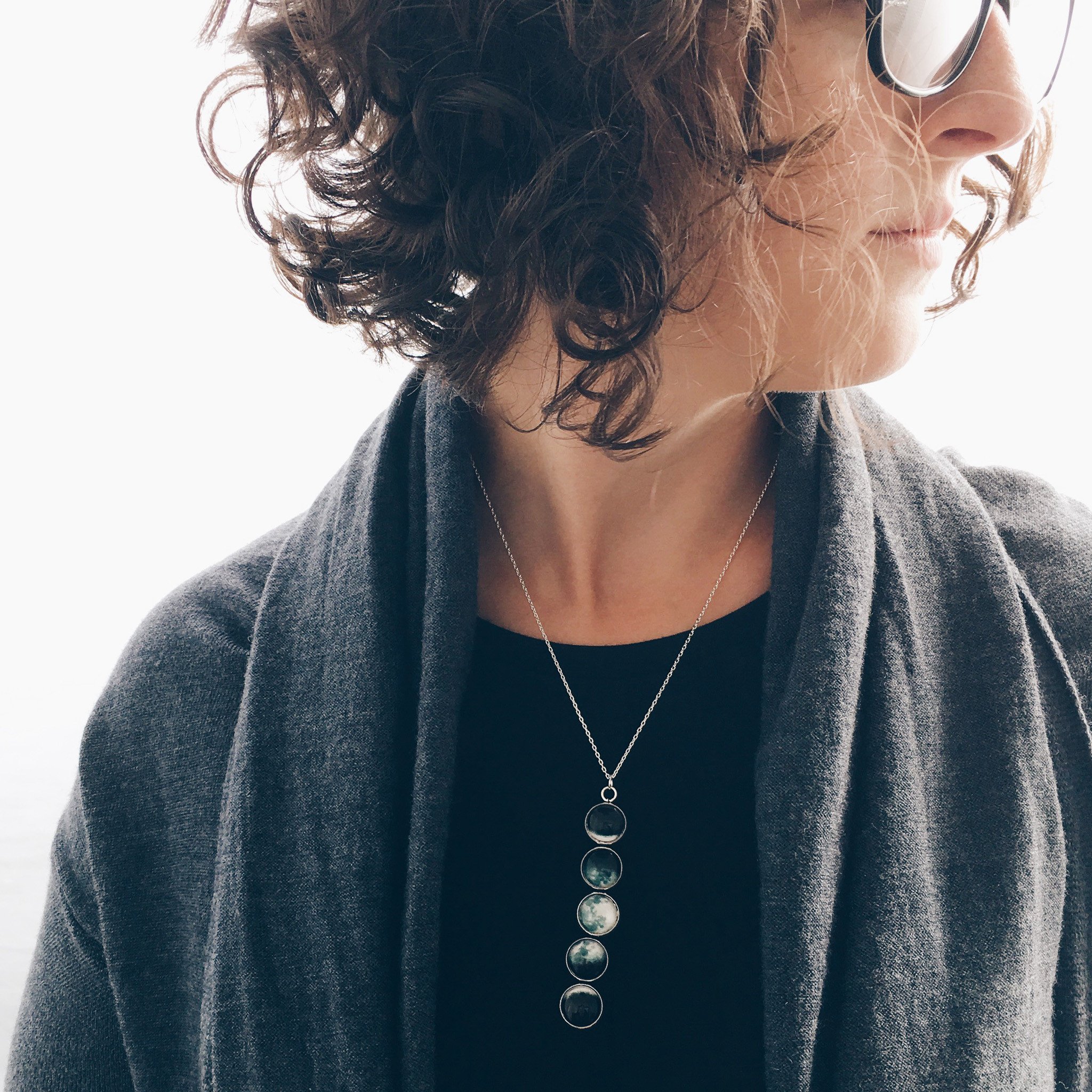 Moon Phase Pendant Necklace featuring silver tone bezels with lunar designs, elegantly hanging from an 18-inch chain.