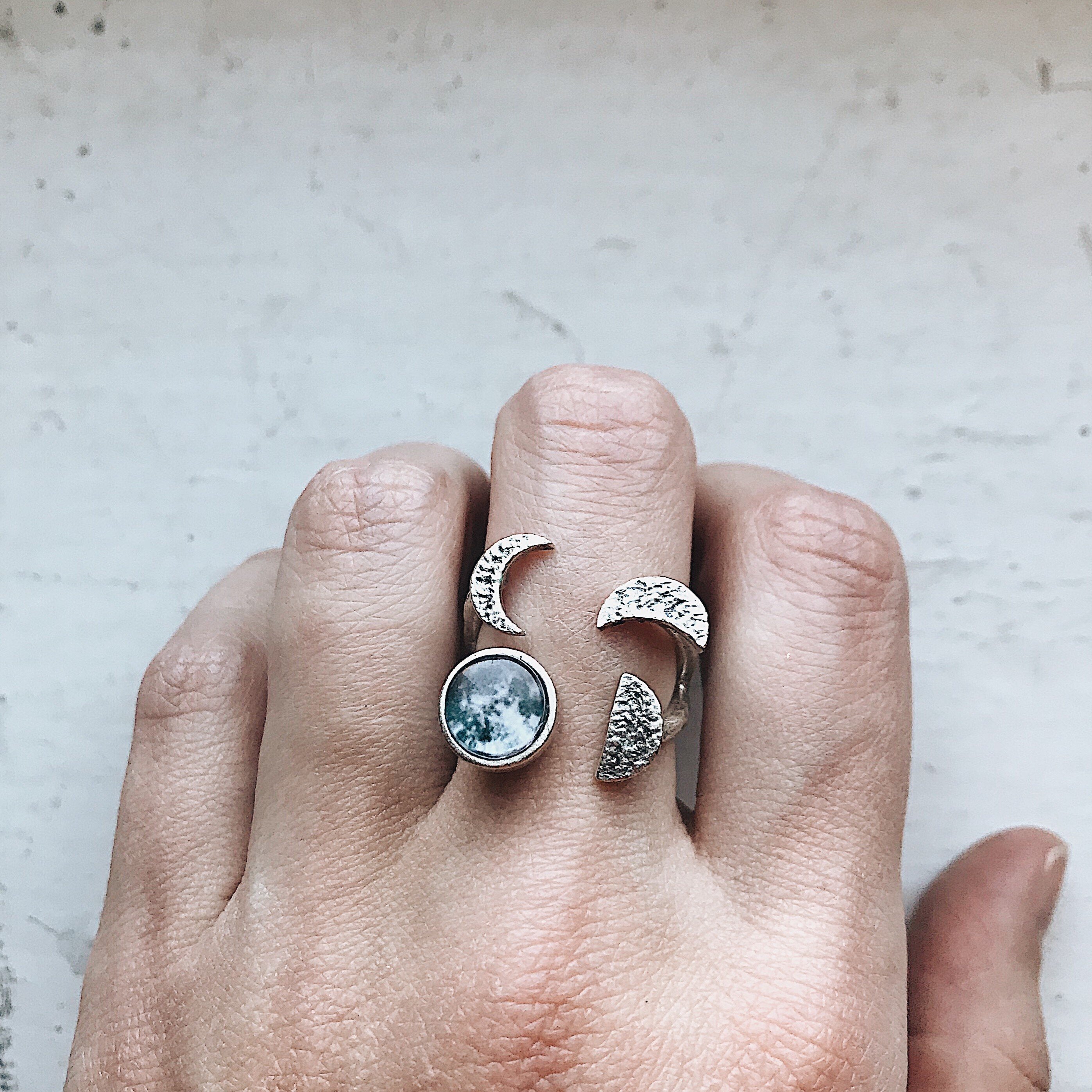 Moon Phase Sculpture Ring featuring hammered design with glass moon phases in silver and gold tones, adjustable size for comfort.