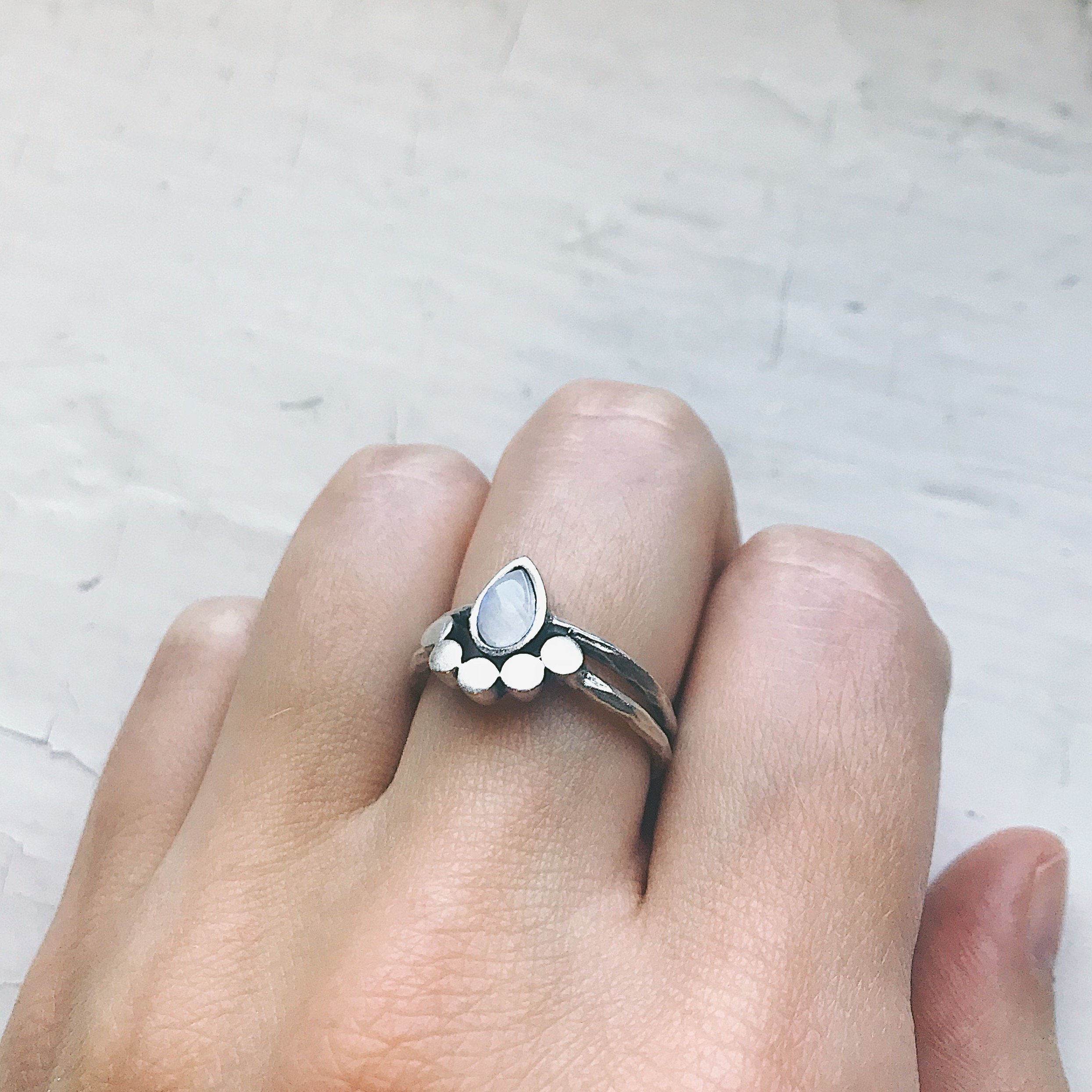 Moondrop Moonstone Ring featuring a teardrop rainbow Moonstone in a bezel surrounded by beads, available in silver and gold tone.