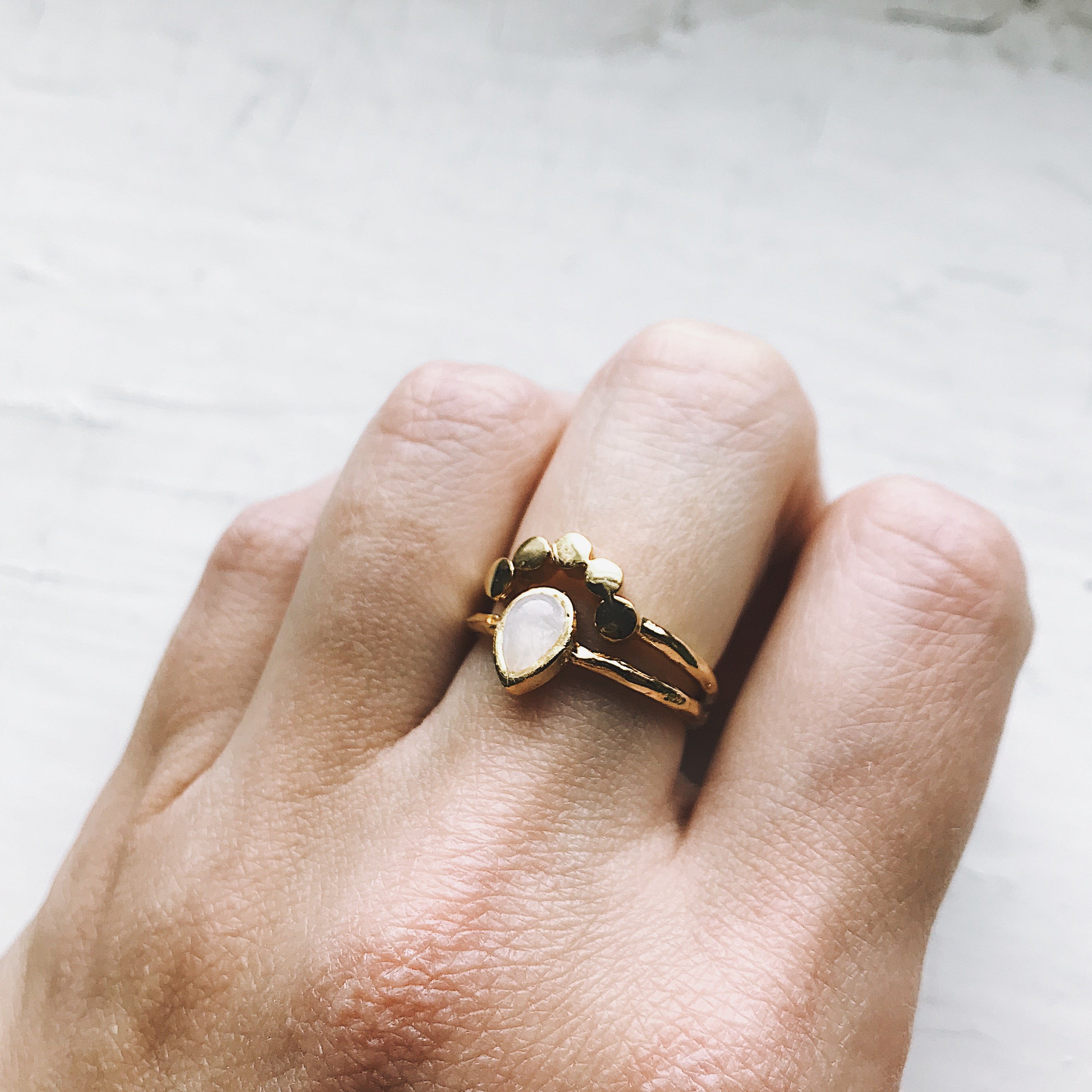 Moondrop Moonstone Ring featuring a teardrop rainbow Moonstone in a bezel surrounded by beads, available in silver and gold tone.