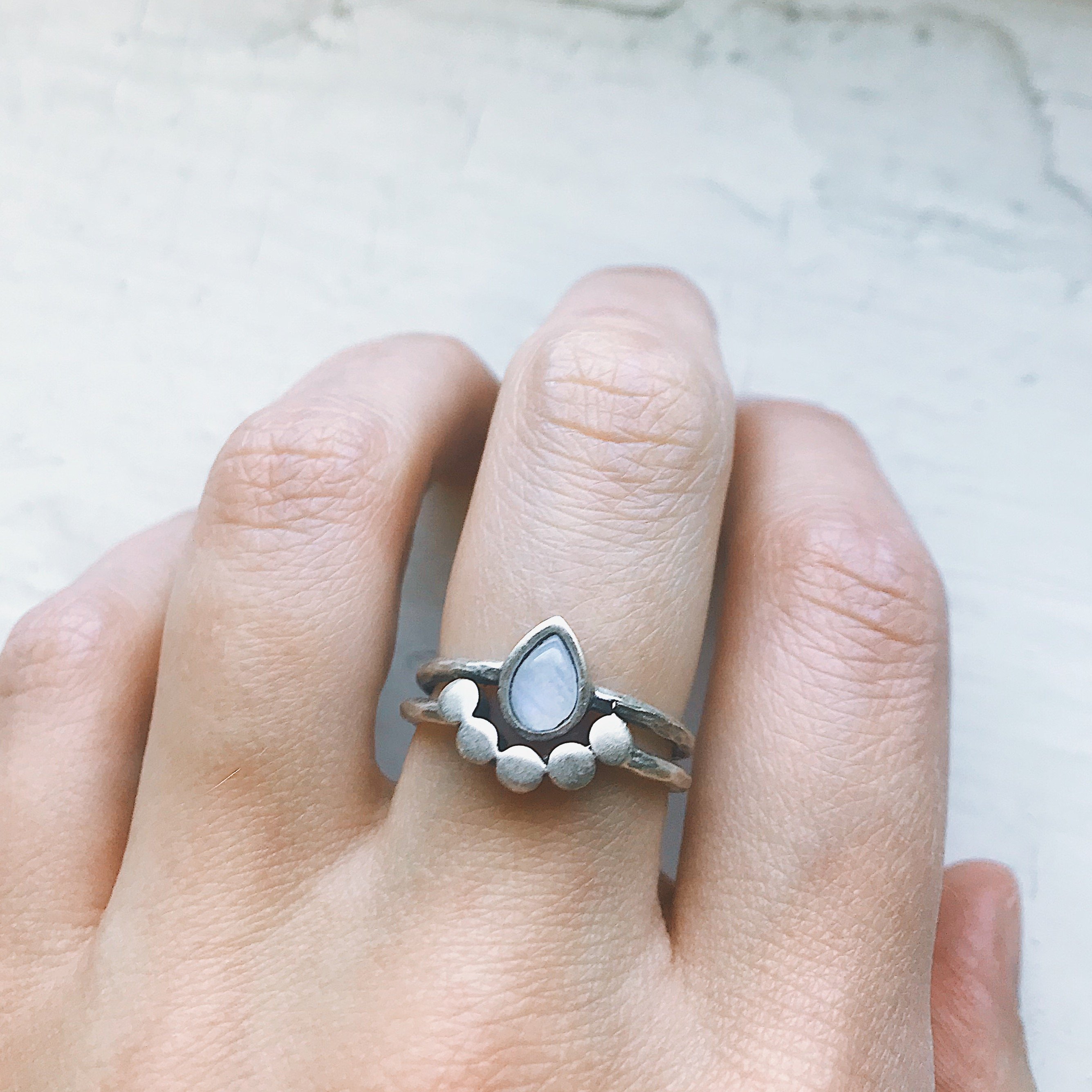 Moondrop Moonstone Ring featuring a teardrop rainbow Moonstone in a bezel surrounded by beads, available in silver and gold tone.