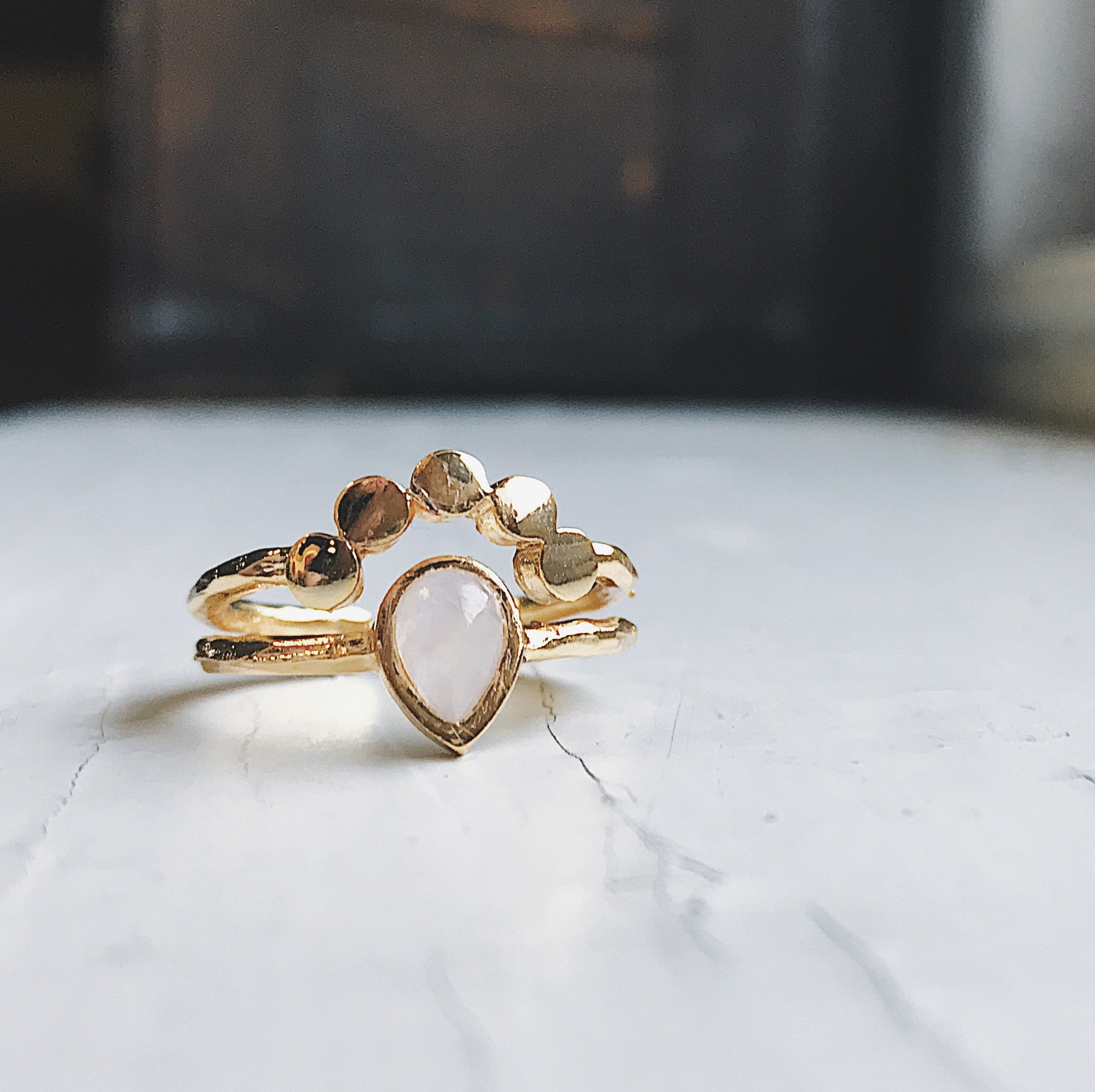 Moondrop Moonstone Ring featuring a teardrop rainbow Moonstone in a bezel surrounded by beads, available in silver and gold tone.