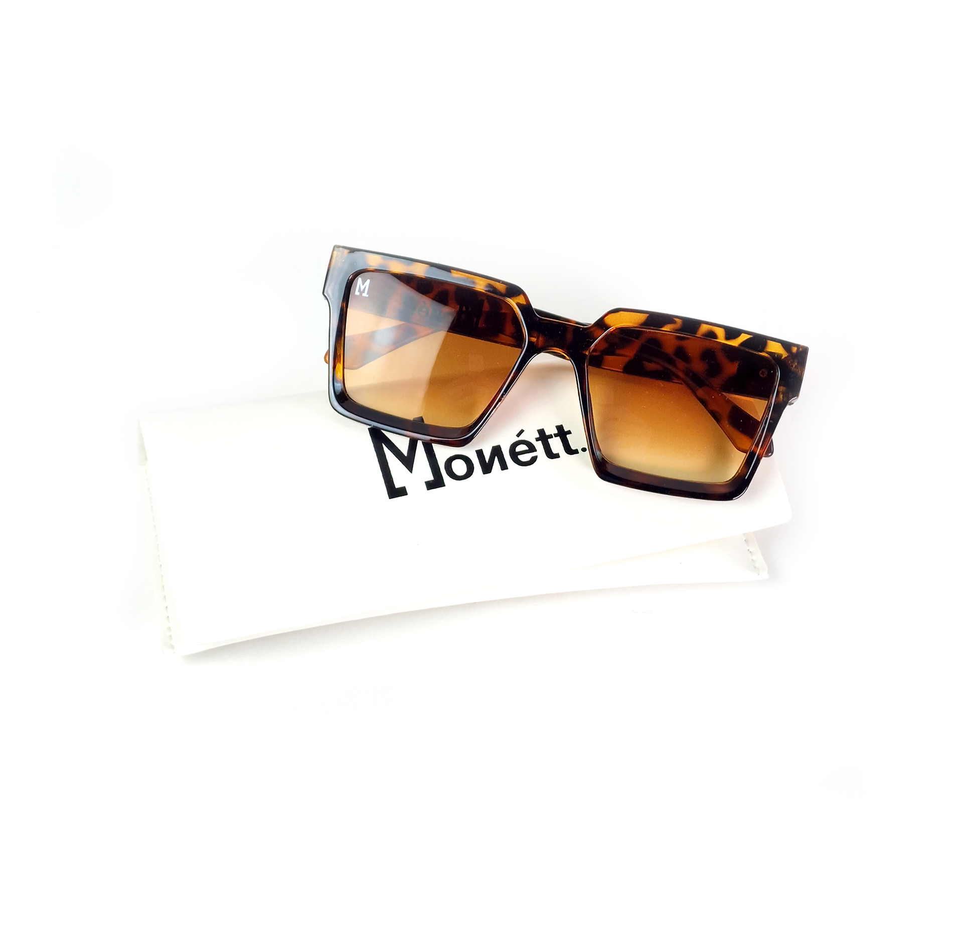 Monett Manifesto Browney sunglasses displayed in a signature box with a cleaning cloth and carry purse.