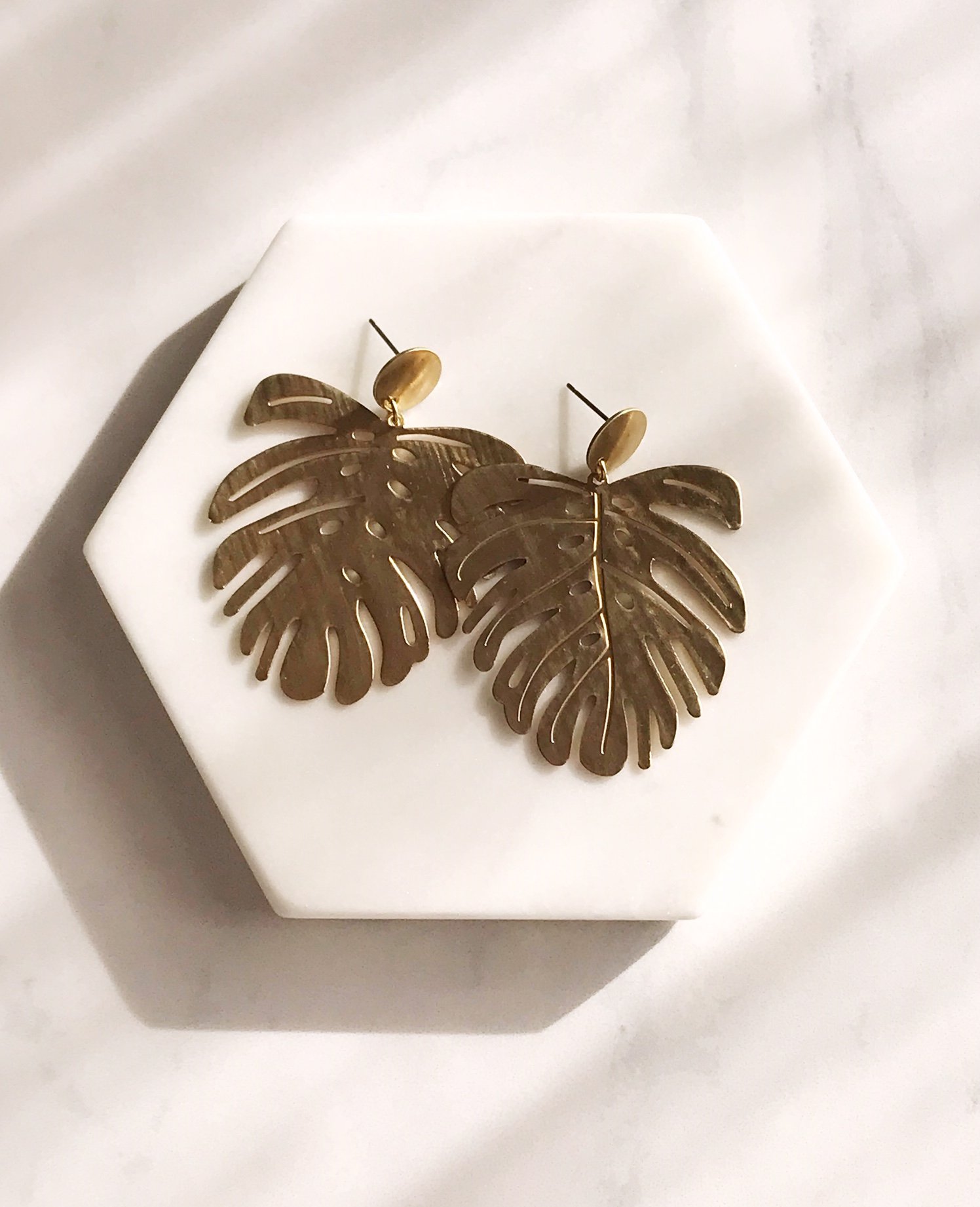 Brushed brass monstera leaf earrings with stainless steel ear posts, showcasing a unique and stylish design.