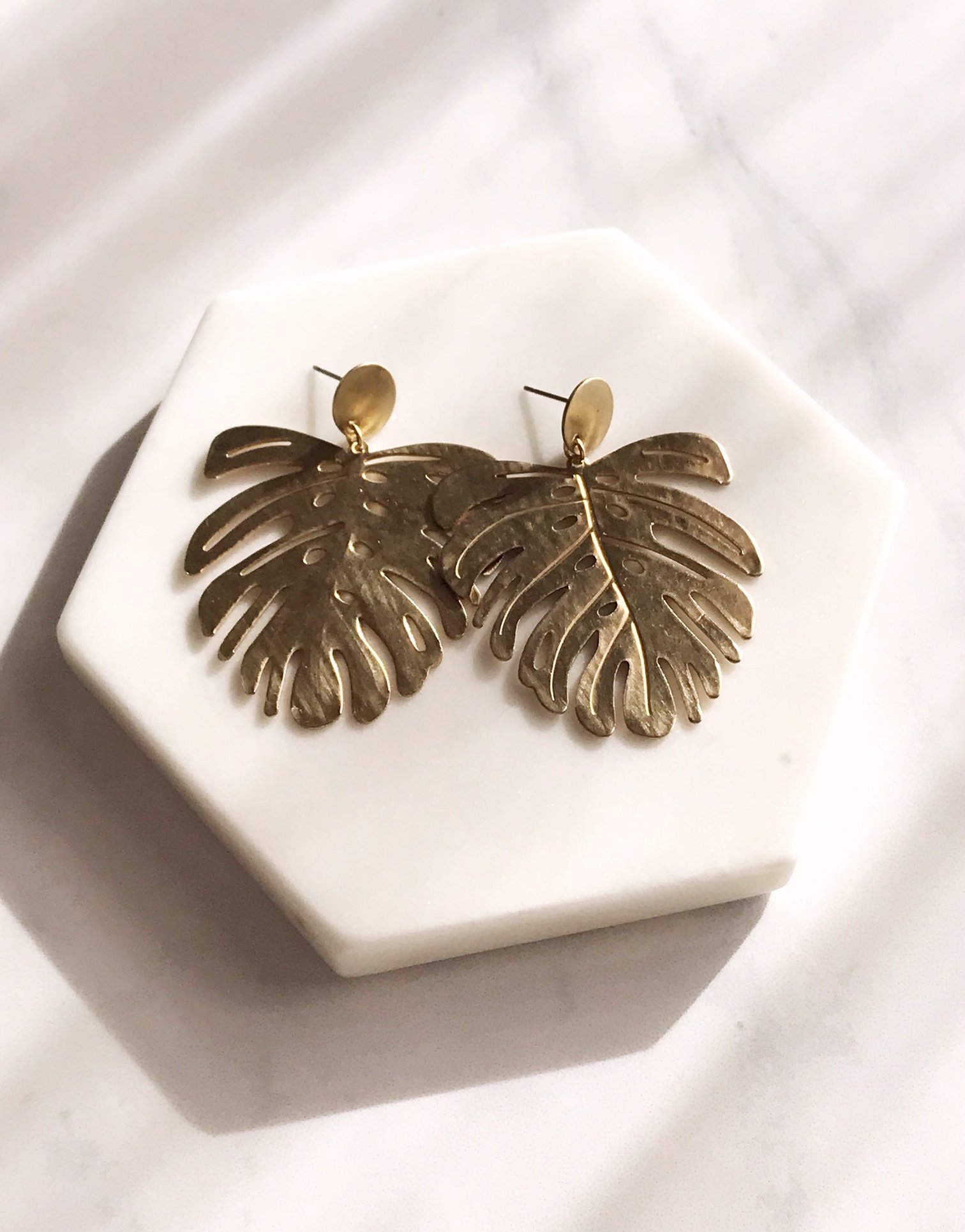 Brushed brass monstera leaf earrings with stainless steel ear posts, showcasing a unique and stylish design.