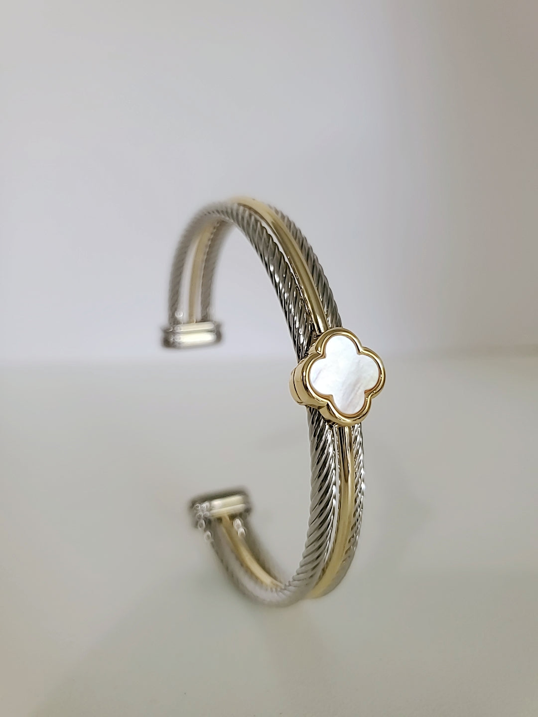 Elegant Mother of Pearl bangle bracelet with 18K Gold Filled clover pattern, showcasing a delicate cable design.