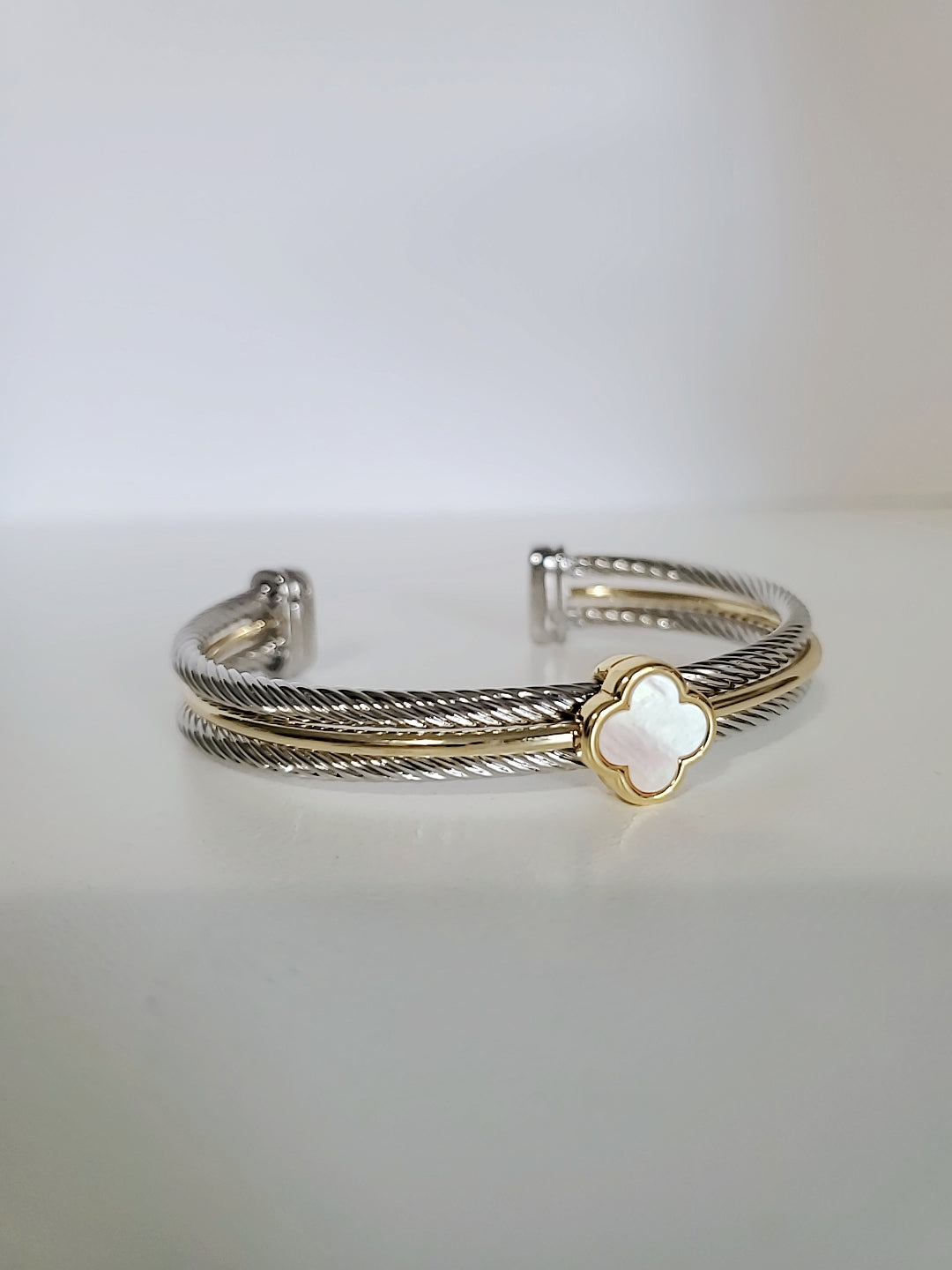 Elegant Mother of Pearl bangle bracelet with 18K Gold Filled clover pattern, showcasing a delicate cable design.