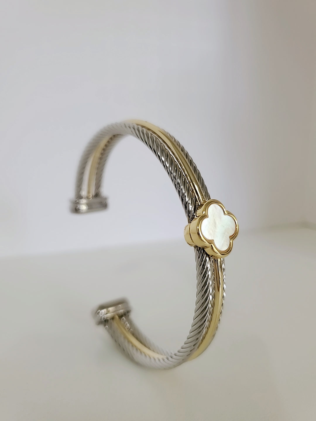 Elegant Mother of Pearl bangle bracelet with 18K Gold Filled clover pattern, showcasing a delicate cable design.