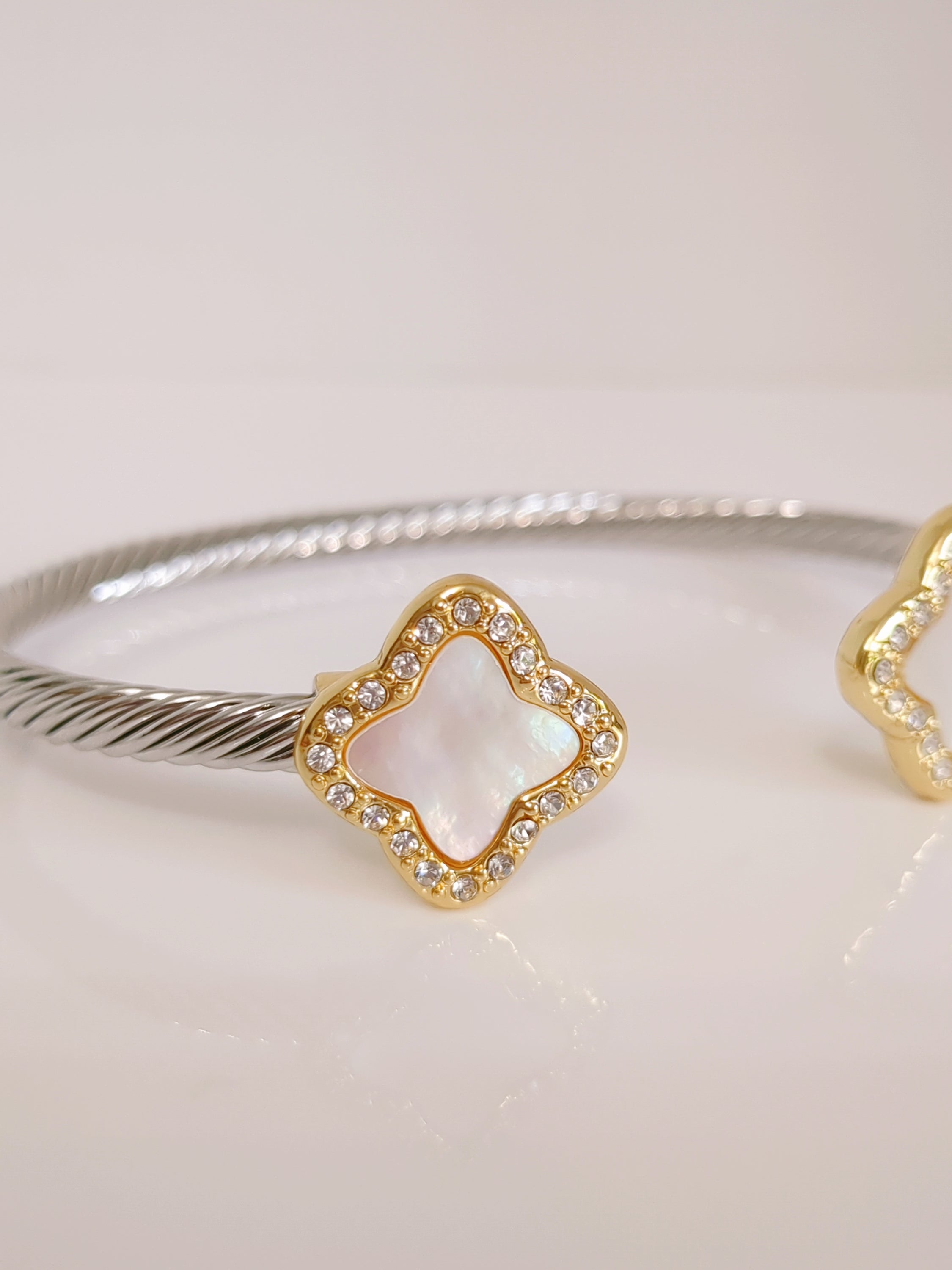 A stylish Mother of Pearl Clover Bangle Bracelet featuring a clover design, crafted from stainless steel with a gold plated finish.