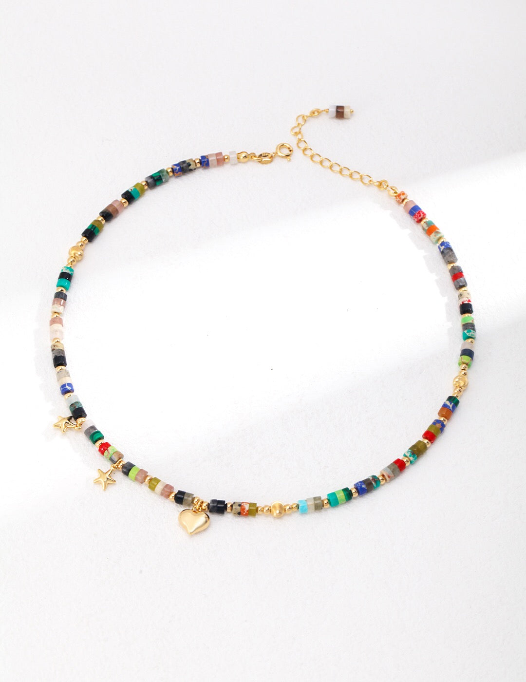 A vibrant multicolored seed bead necklace featuring colored stones and gold vermeil accents, elegantly displayed on a soft background.