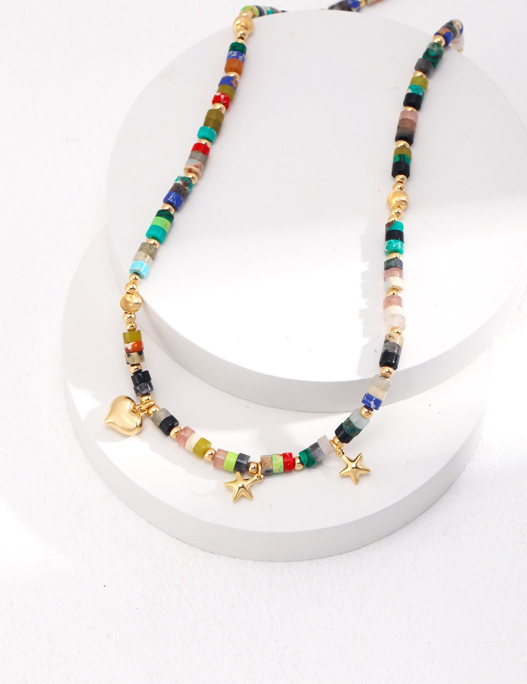 A vibrant multicolored seed bead necklace featuring colored stones and gold vermeil accents, elegantly displayed on a soft background.