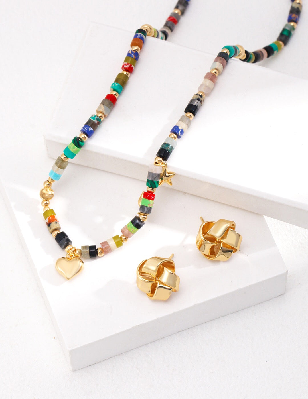 A vibrant multicolored seed bead necklace featuring colored stones and gold vermeil accents, elegantly displayed on a soft background.