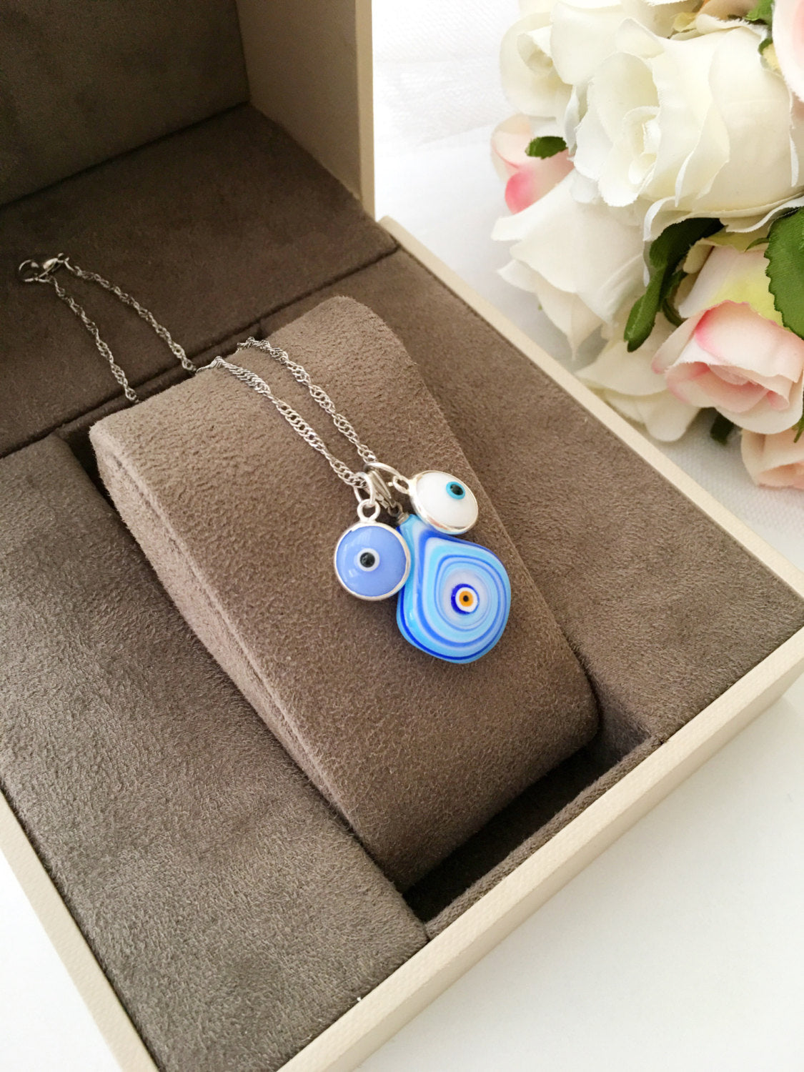 A beautiful Murano glass evil eye necklace featuring a large blue evil eye bead and tiny turquoise and white beads, symbolizing protection and good luck.