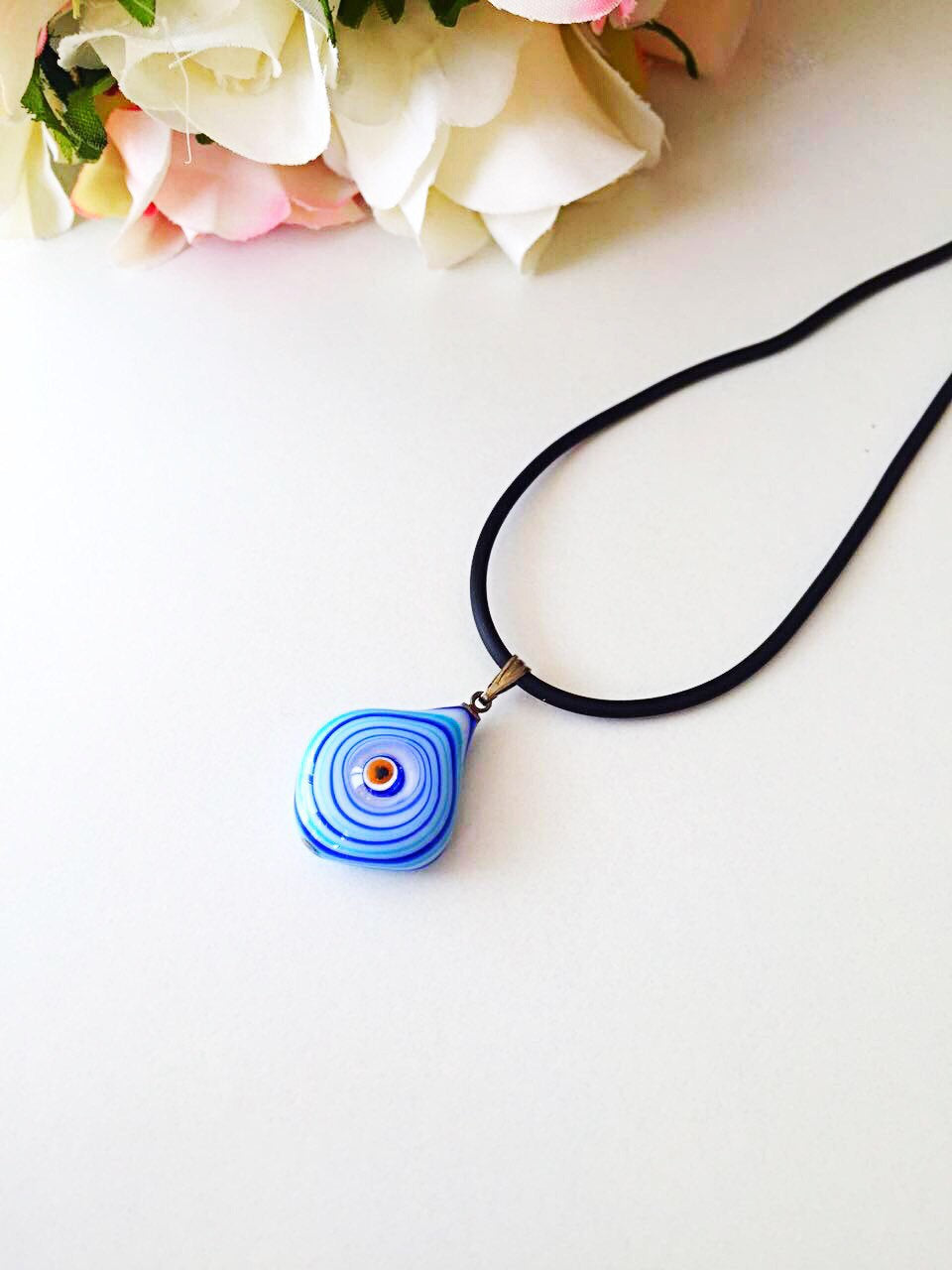 A beautiful Murano glass evil eye pendant featuring a vibrant blue lampwork bead, symbolizing protection and good luck.