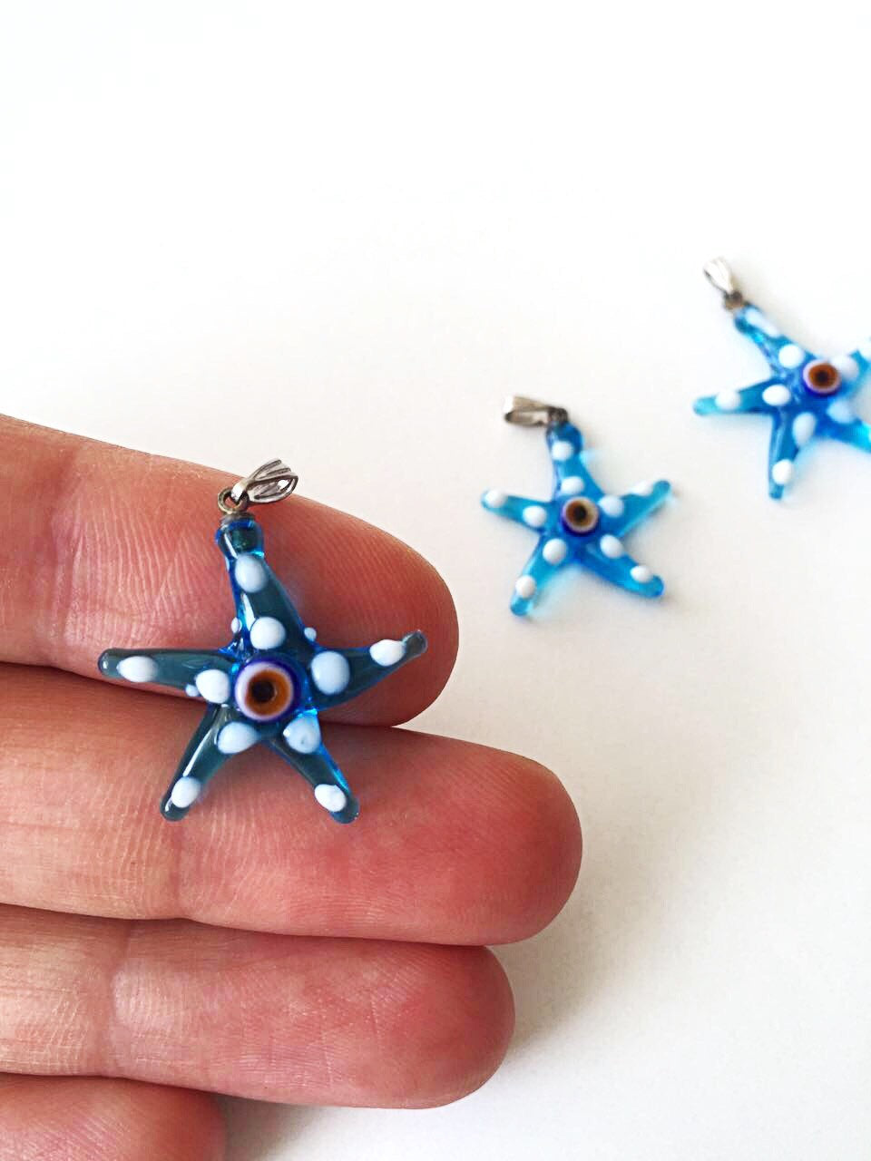 Murano glass evil eye starfish pendant in blue, showcasing intricate lampwork design and vibrant colors.