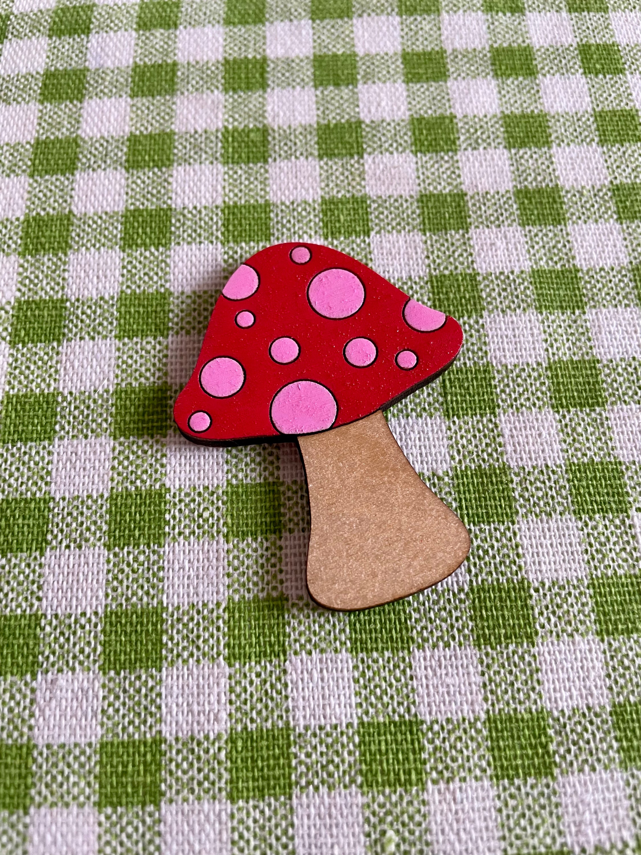 A wooden mushroom brooch and hairclip featuring spots, made from sustainable Birch Plywood, showcasing a vintage-inspired design.