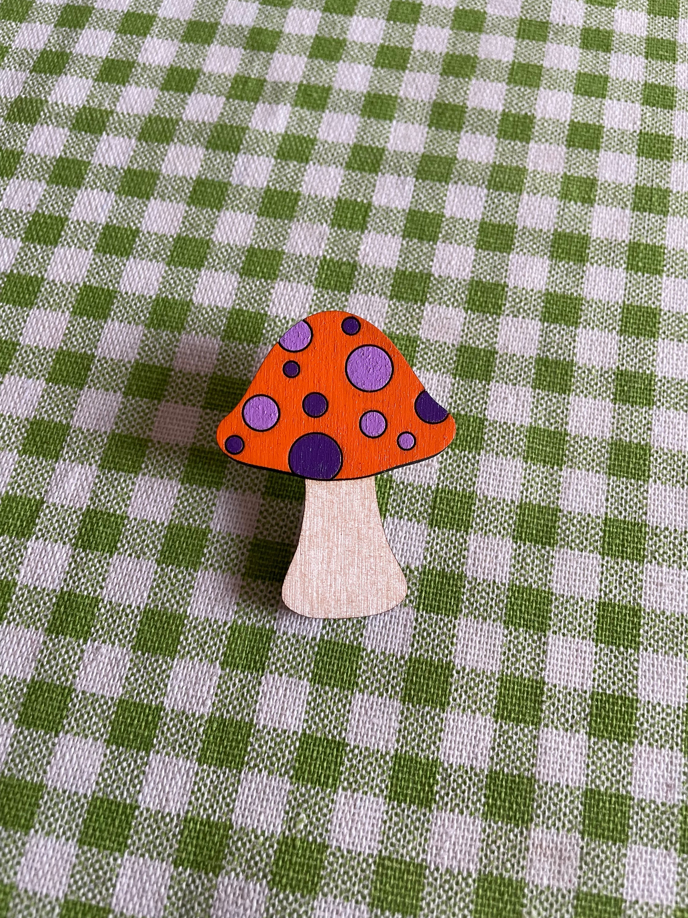 A wooden mushroom brooch and hairclip featuring spots, made from sustainable Birch Plywood, showcasing a vintage-inspired design.