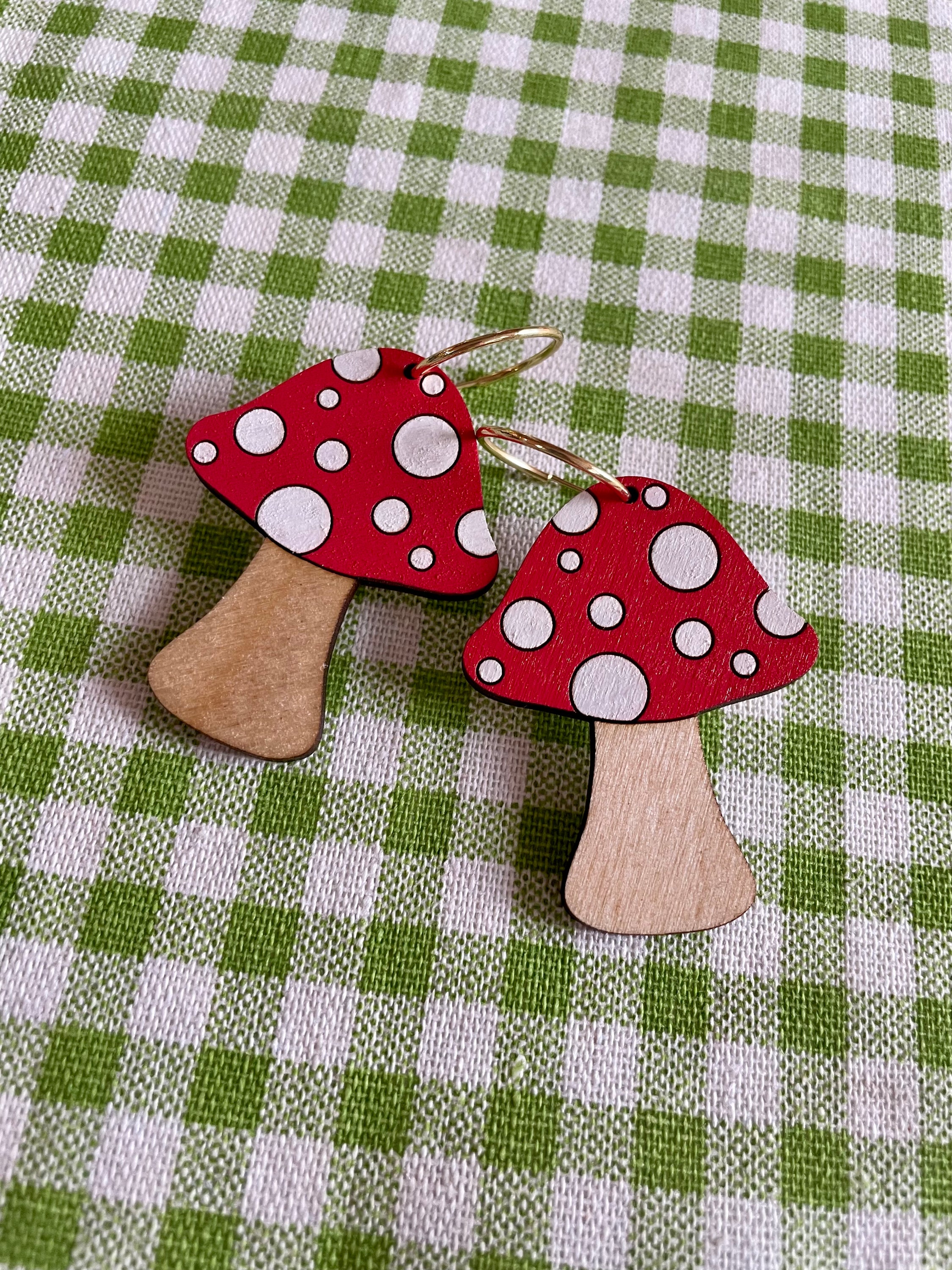 A pair of wooden mushroom earrings featuring spots, crafted from sustainable Birch Plywood, showcasing a whimsical design.