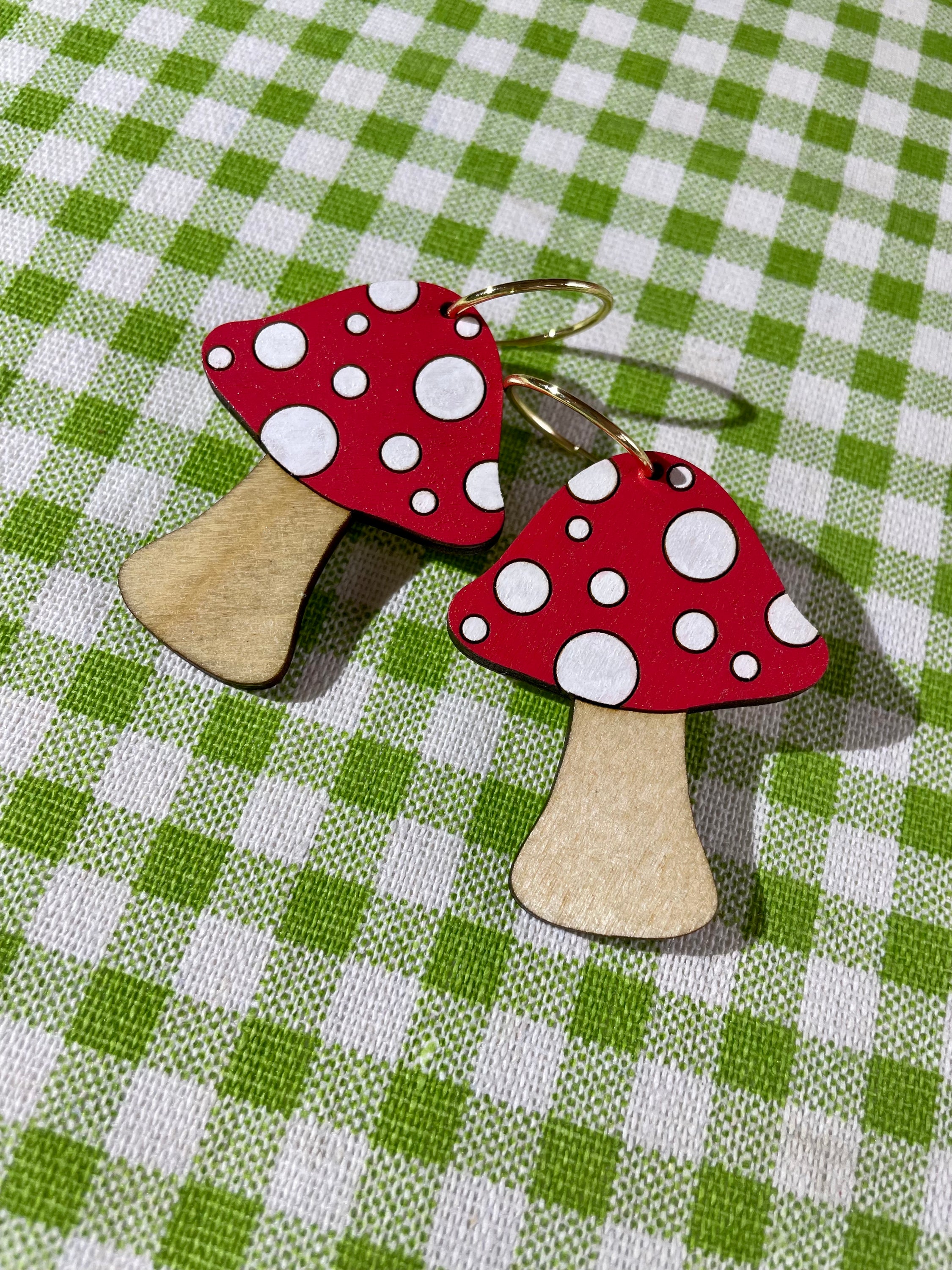 A pair of wooden mushroom earrings featuring spots, crafted from sustainable Birch Plywood, showcasing a whimsical design.