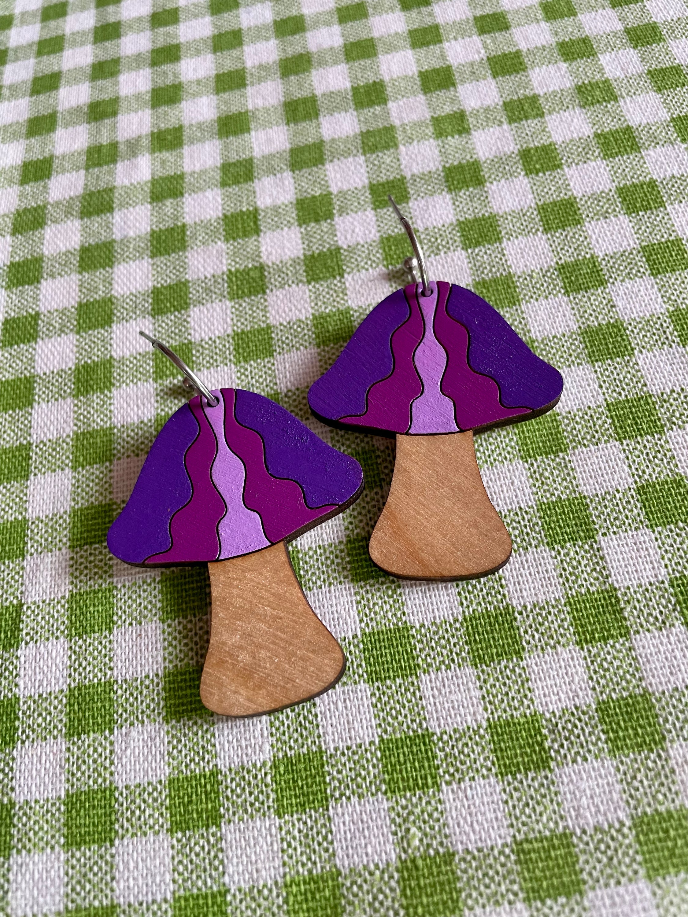 A pair of handcrafted wooden mushroom earrings in waves design, made from sustainable Birch Plywood, showcasing vibrant colors and intricate details.