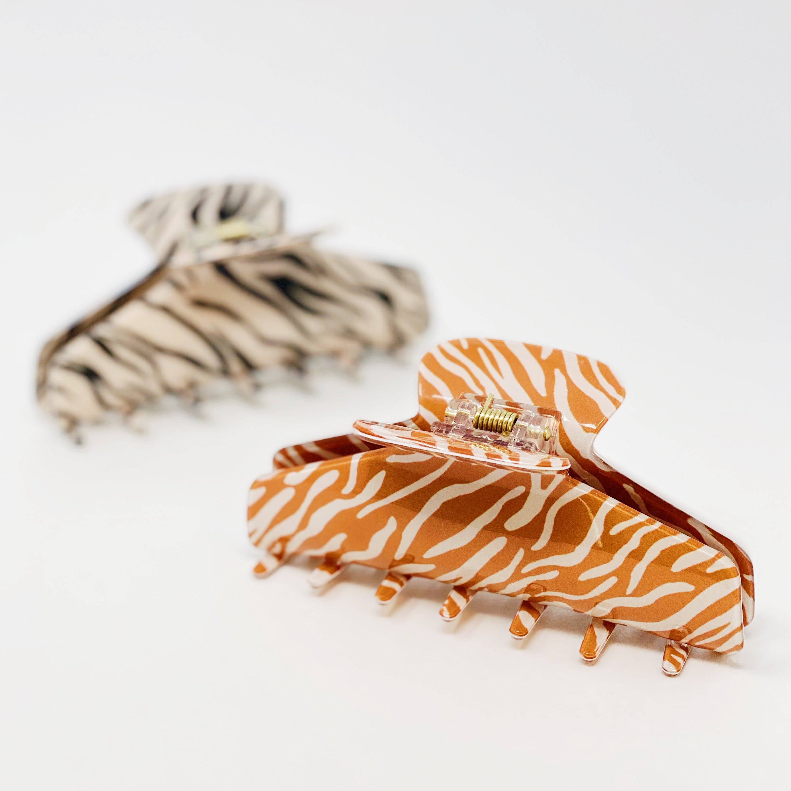 Muted zebra print hair claw clip made of durable acrylic, designed to hold thick hair securely with a stylish aesthetic.