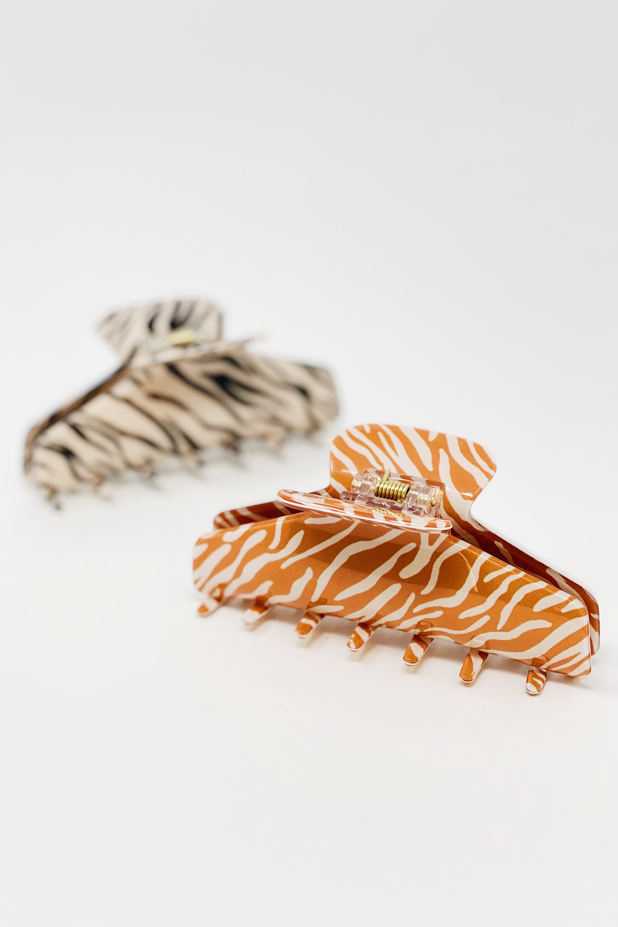 Muted zebra print hair claw clip made of durable acrylic, designed to hold thick hair securely with a stylish aesthetic.