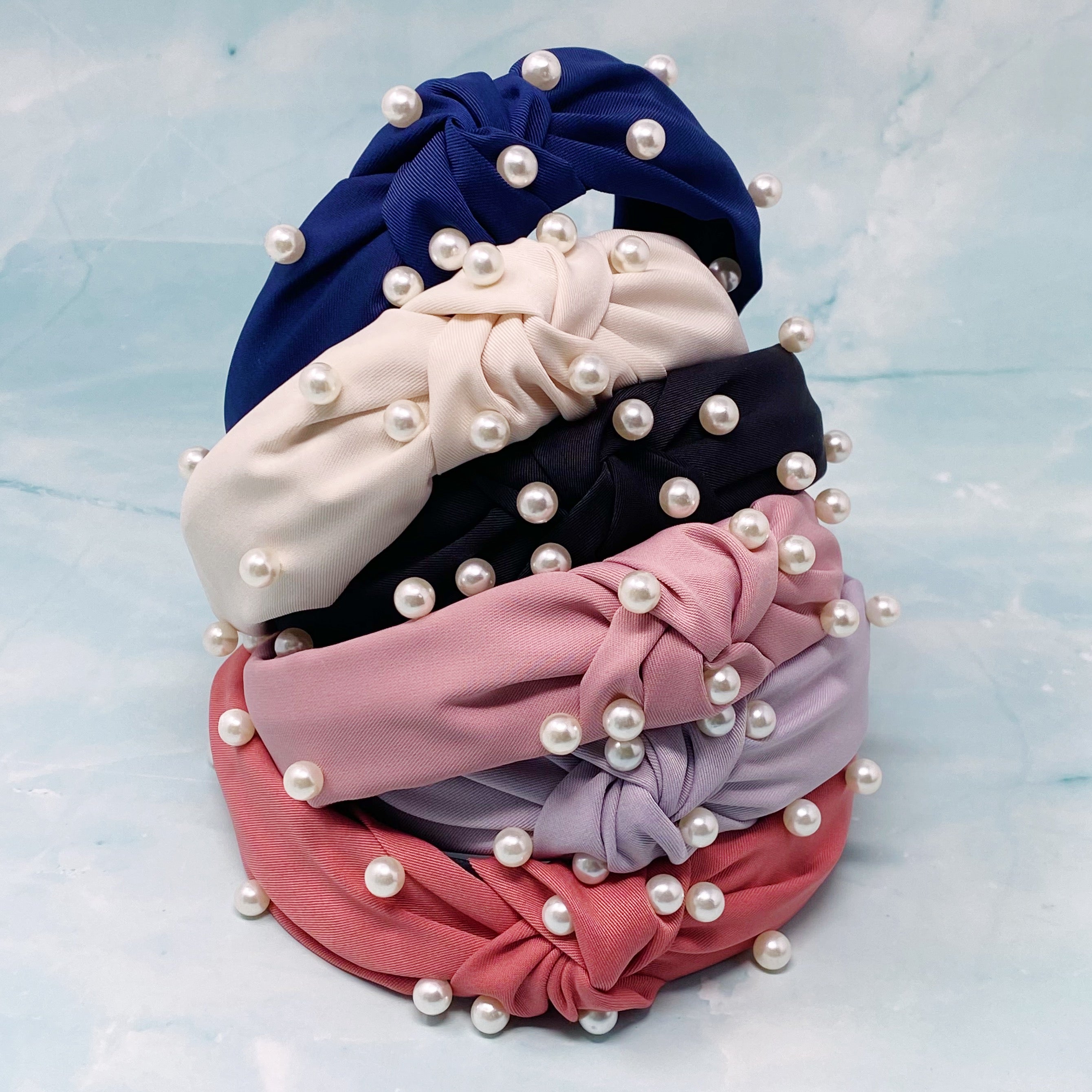 A stylish knotted headband adorned with pearls, perfect for enhancing any outfit.