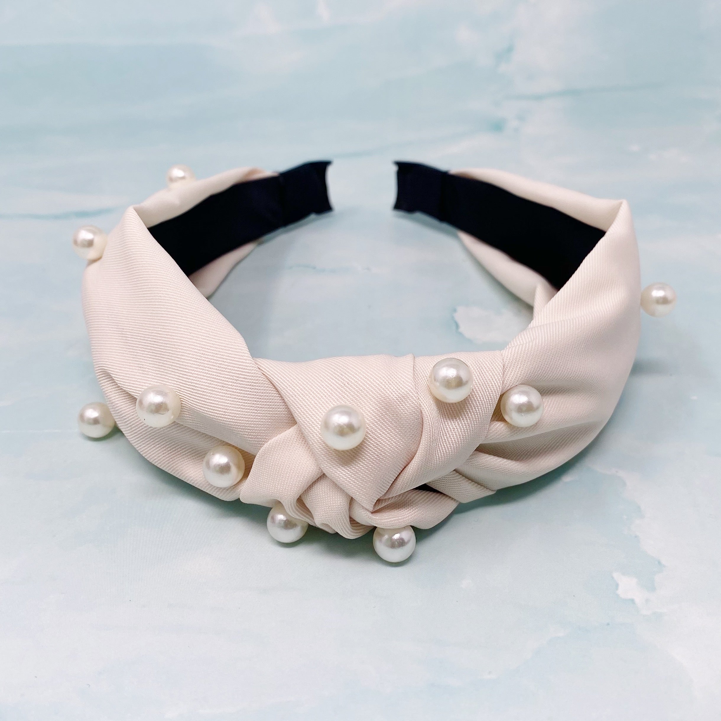 A stylish knotted headband adorned with pearls, perfect for enhancing any outfit.