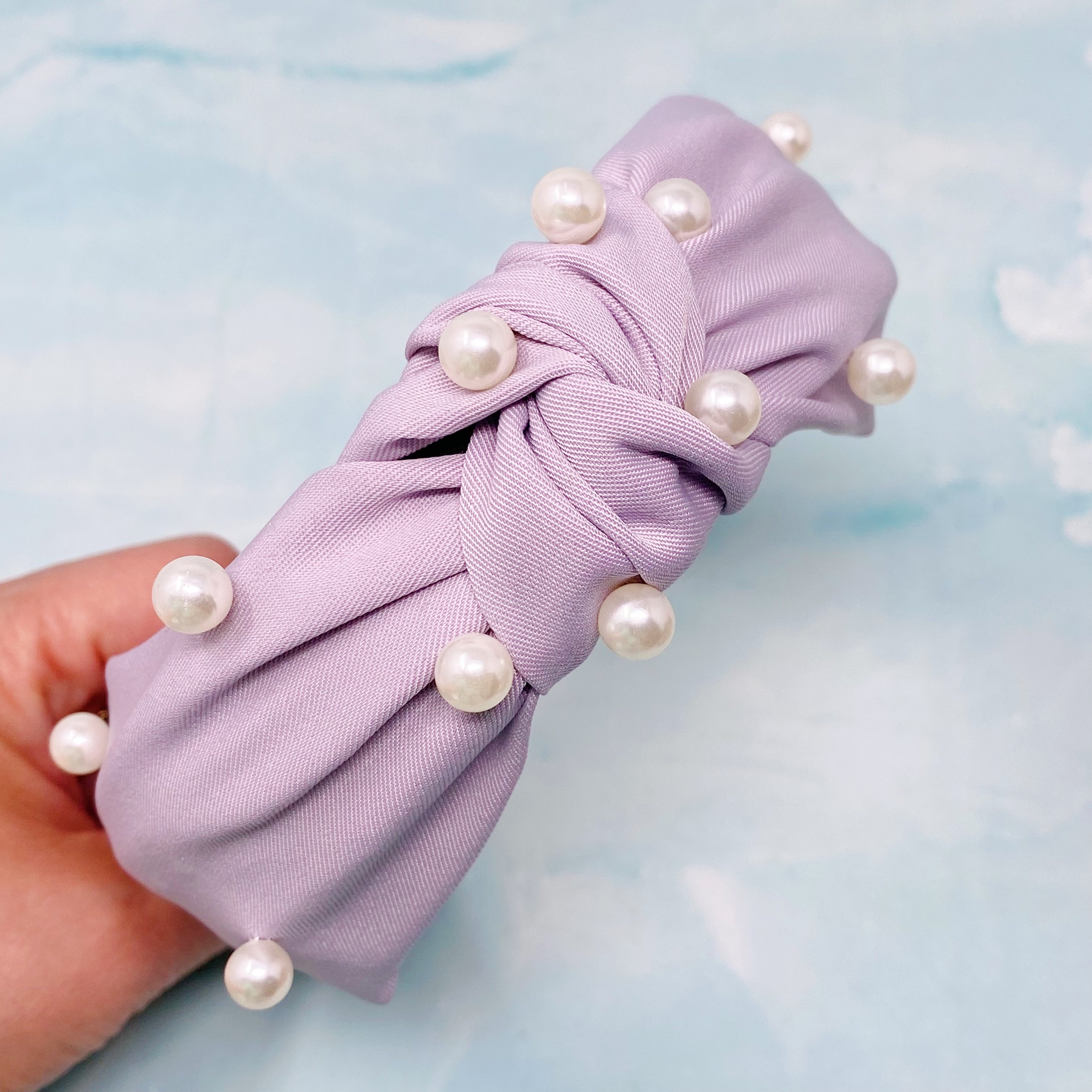 A stylish knotted headband adorned with pearls, perfect for enhancing any outfit.