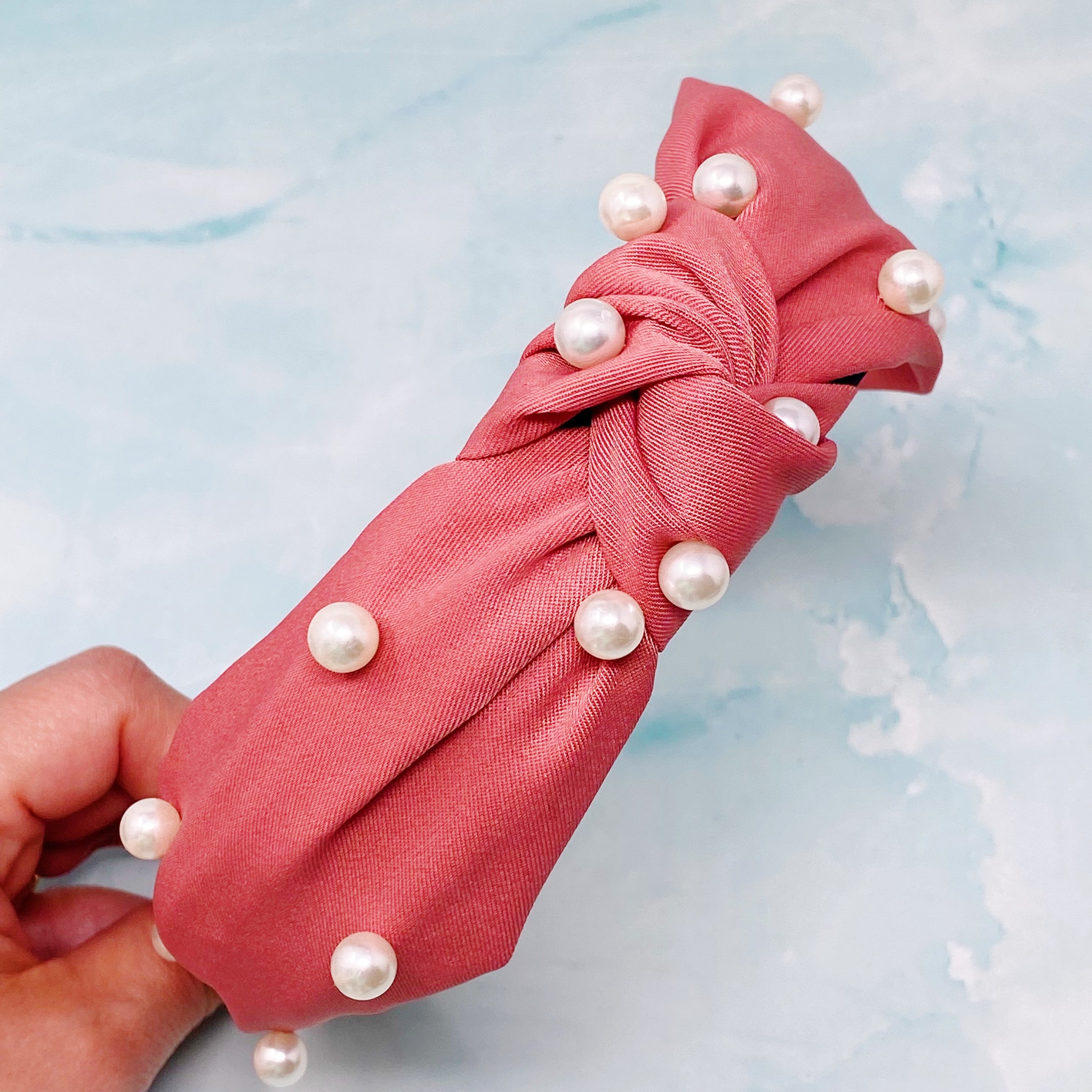 A stylish knotted headband adorned with pearls, perfect for enhancing any outfit.