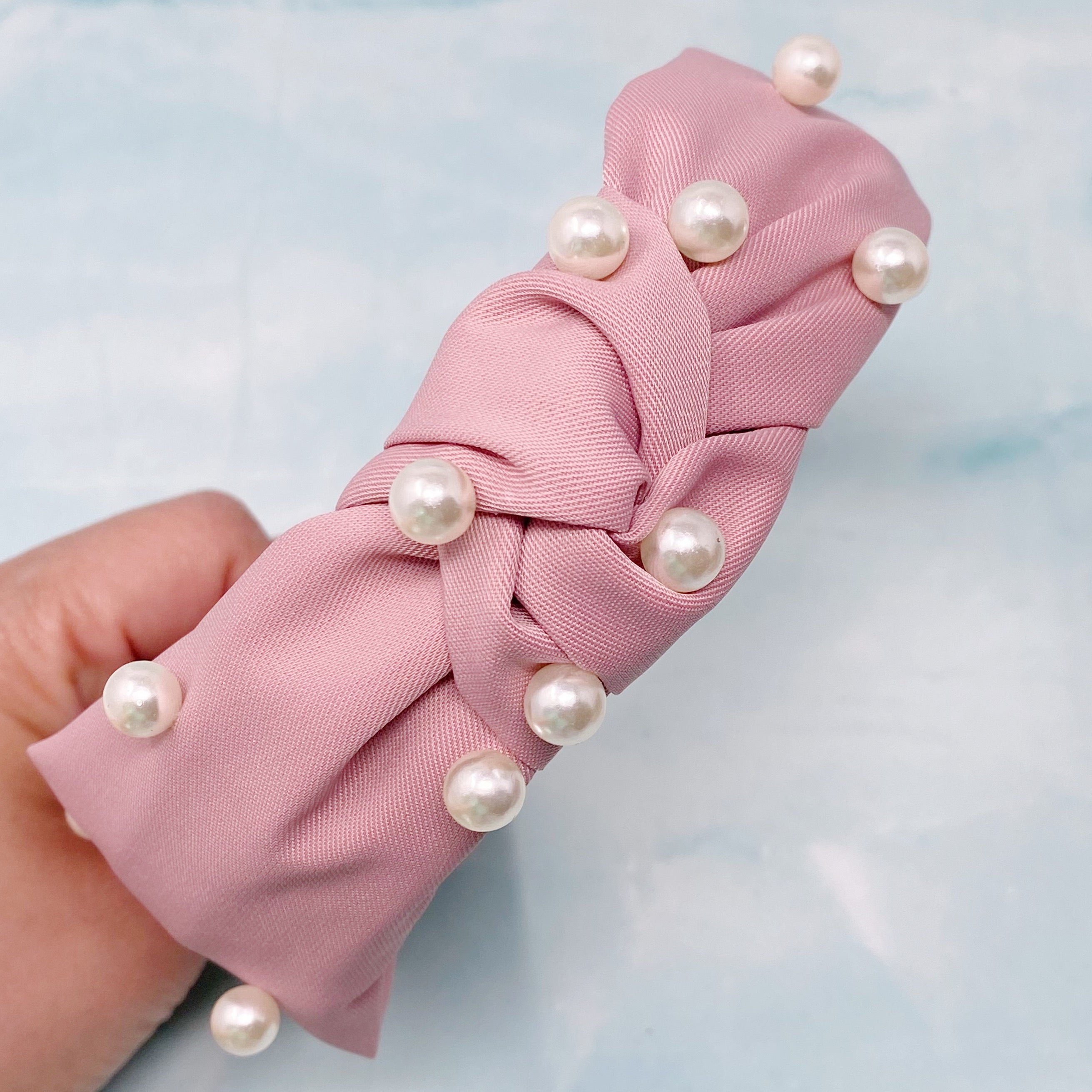 A stylish knotted headband adorned with pearls, perfect for enhancing any outfit.