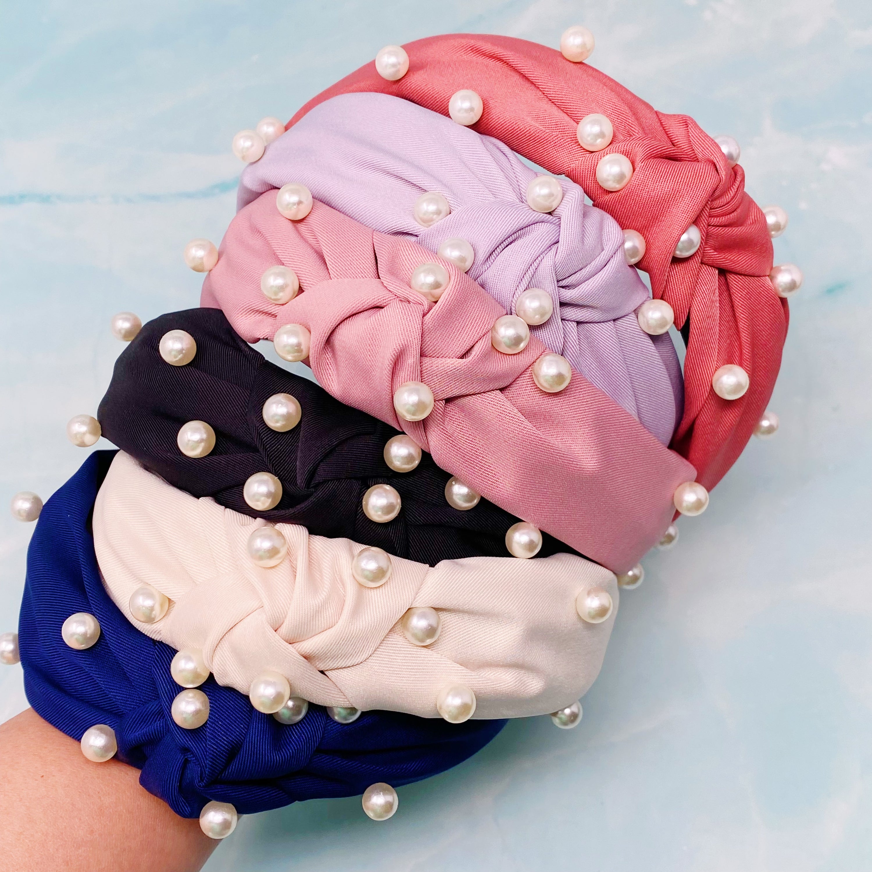 A stylish knotted headband adorned with pearls, perfect for enhancing any outfit.