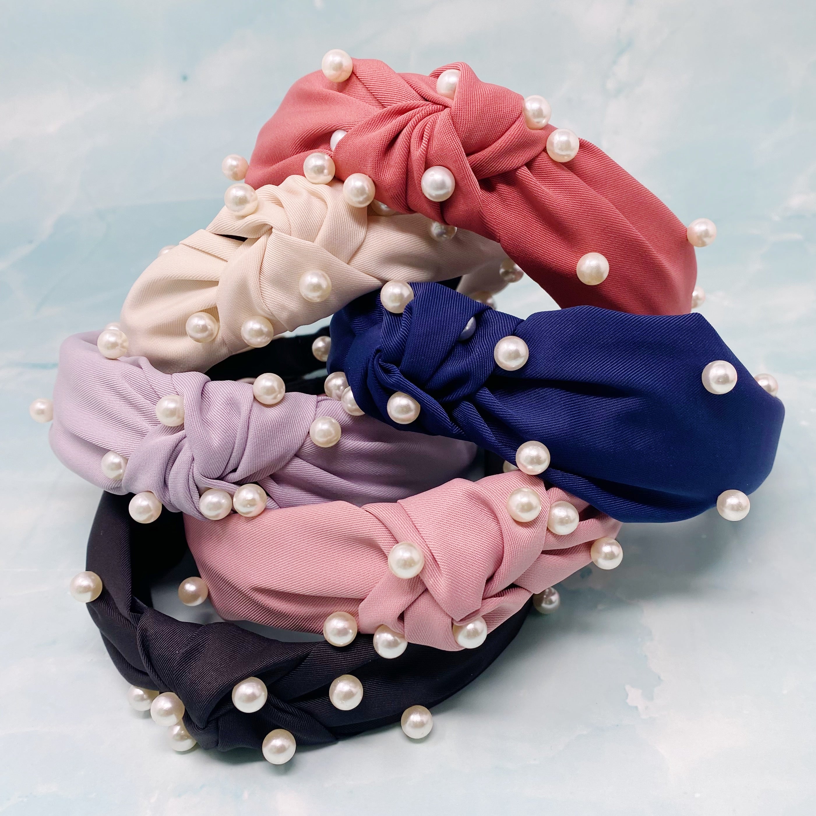 A stylish knotted headband adorned with pearls, perfect for enhancing any outfit.