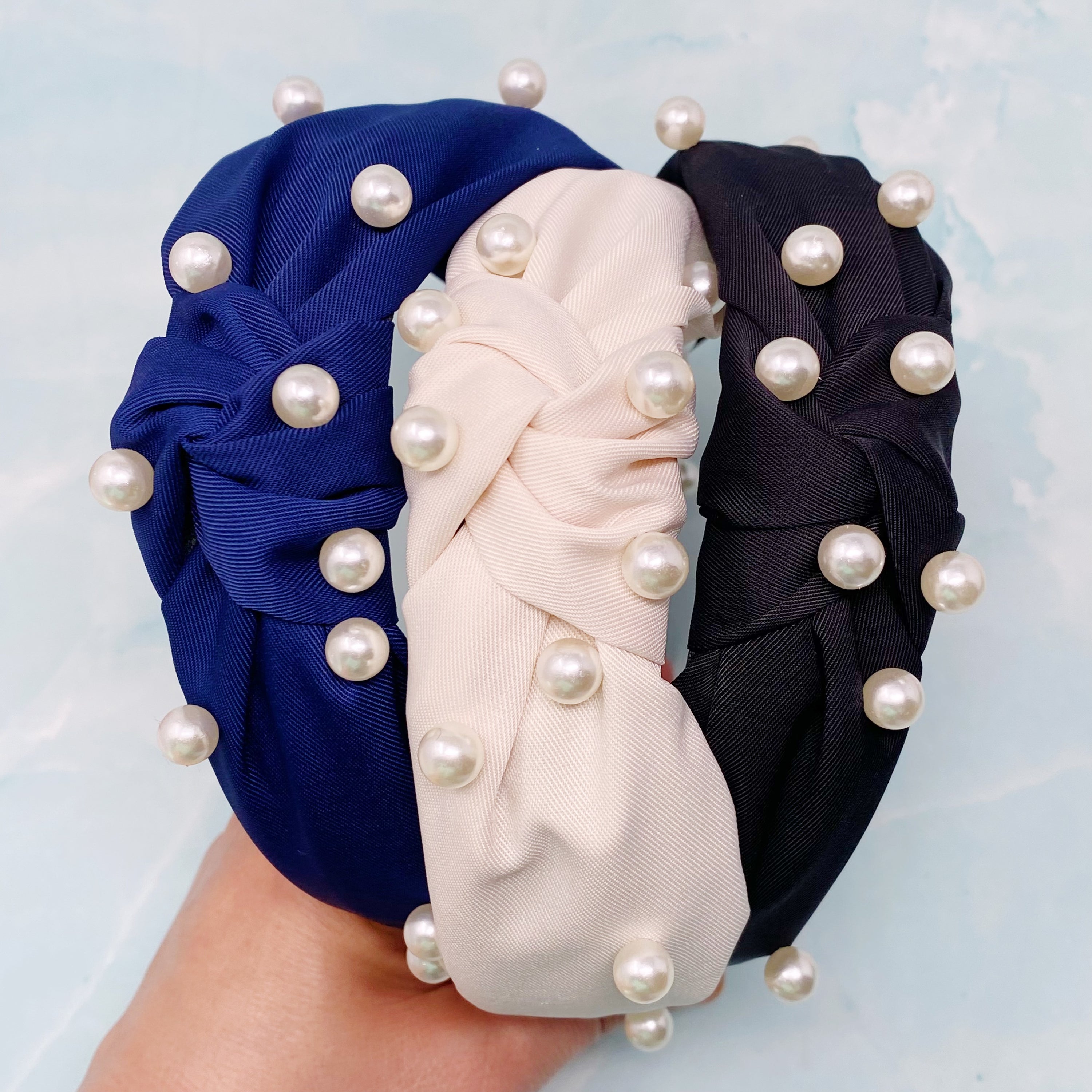 A stylish knotted headband adorned with pearls, perfect for enhancing any outfit.