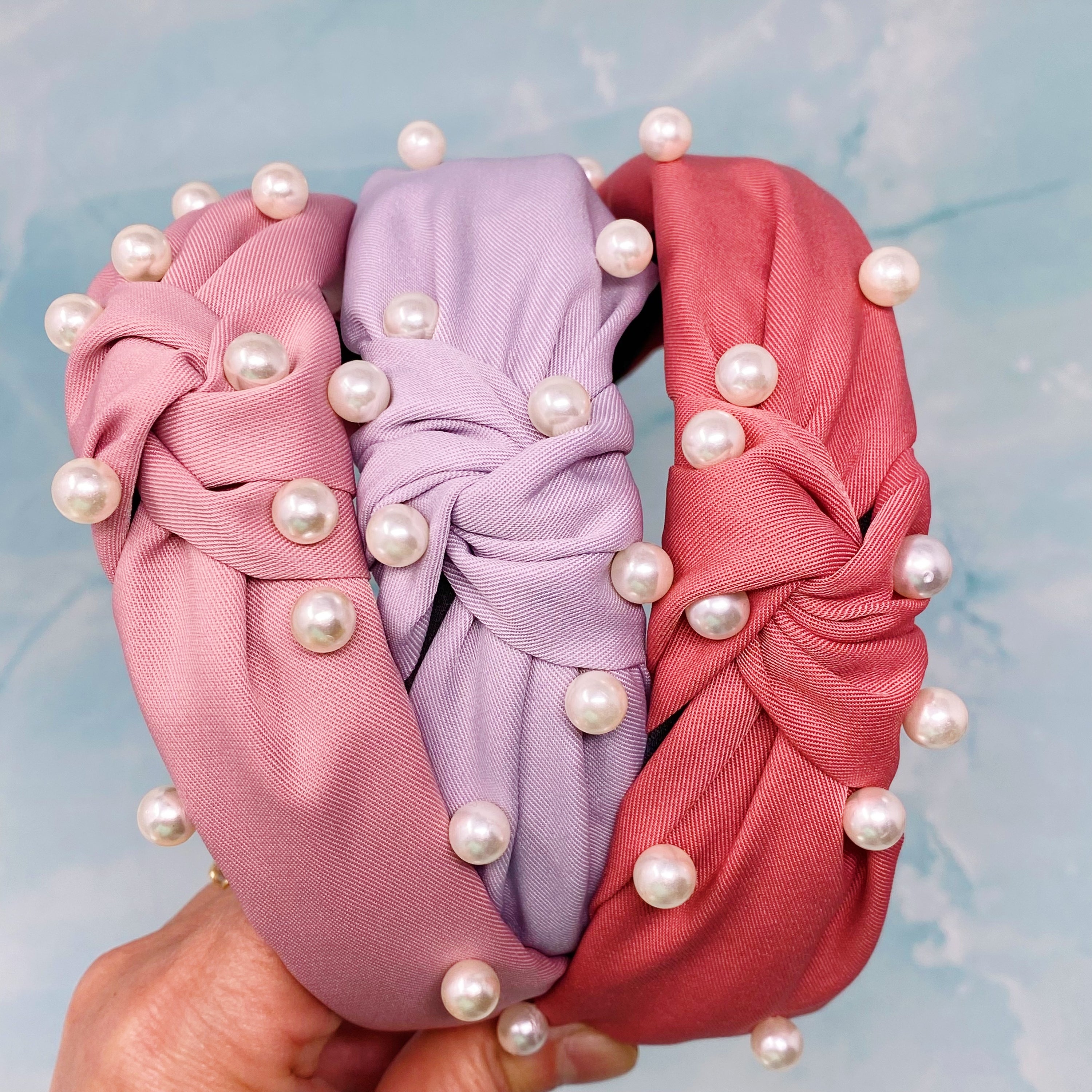 A stylish knotted headband adorned with pearls, perfect for enhancing any outfit.