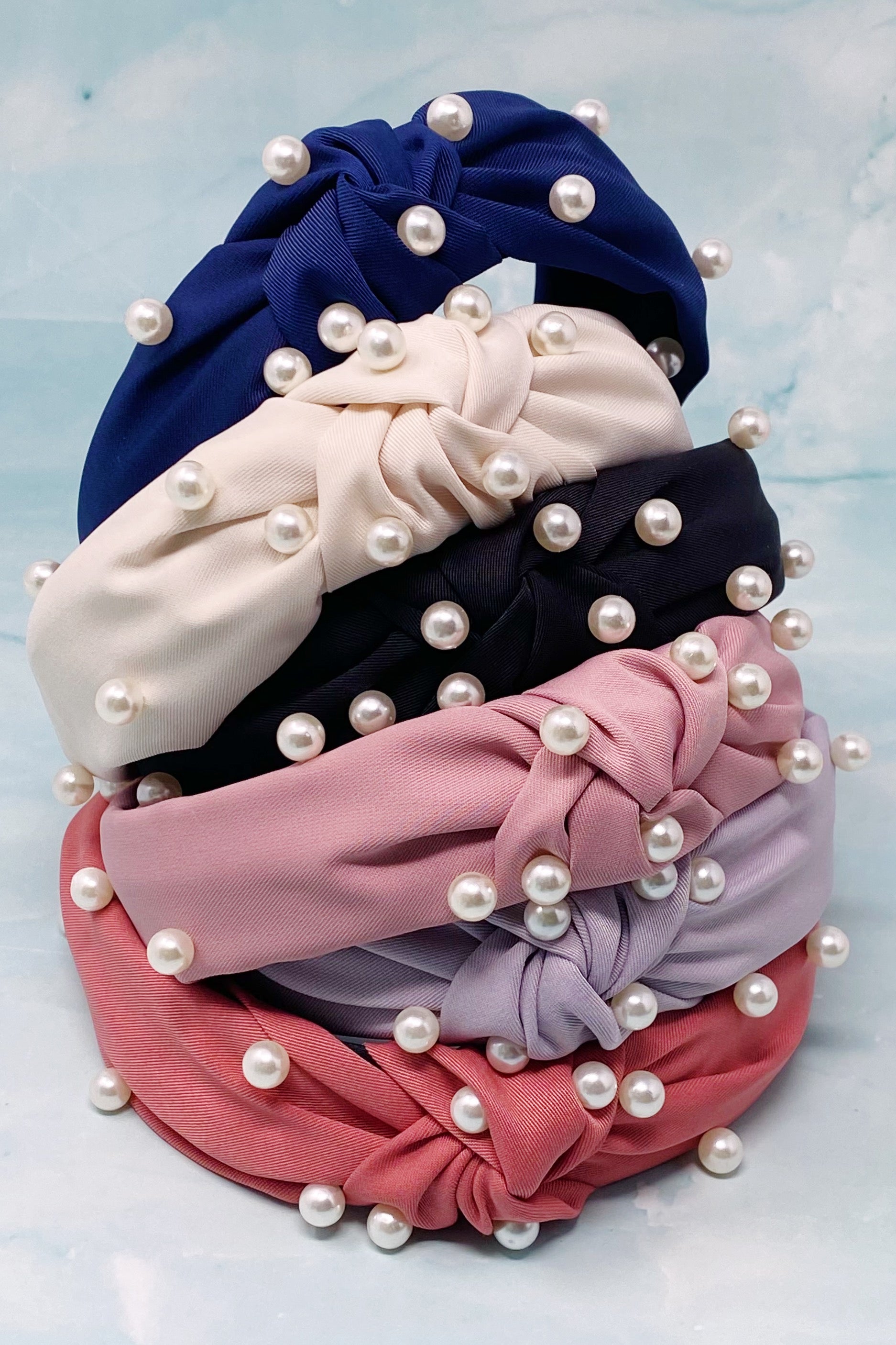 A stylish knotted headband adorned with pearls, perfect for enhancing any outfit.