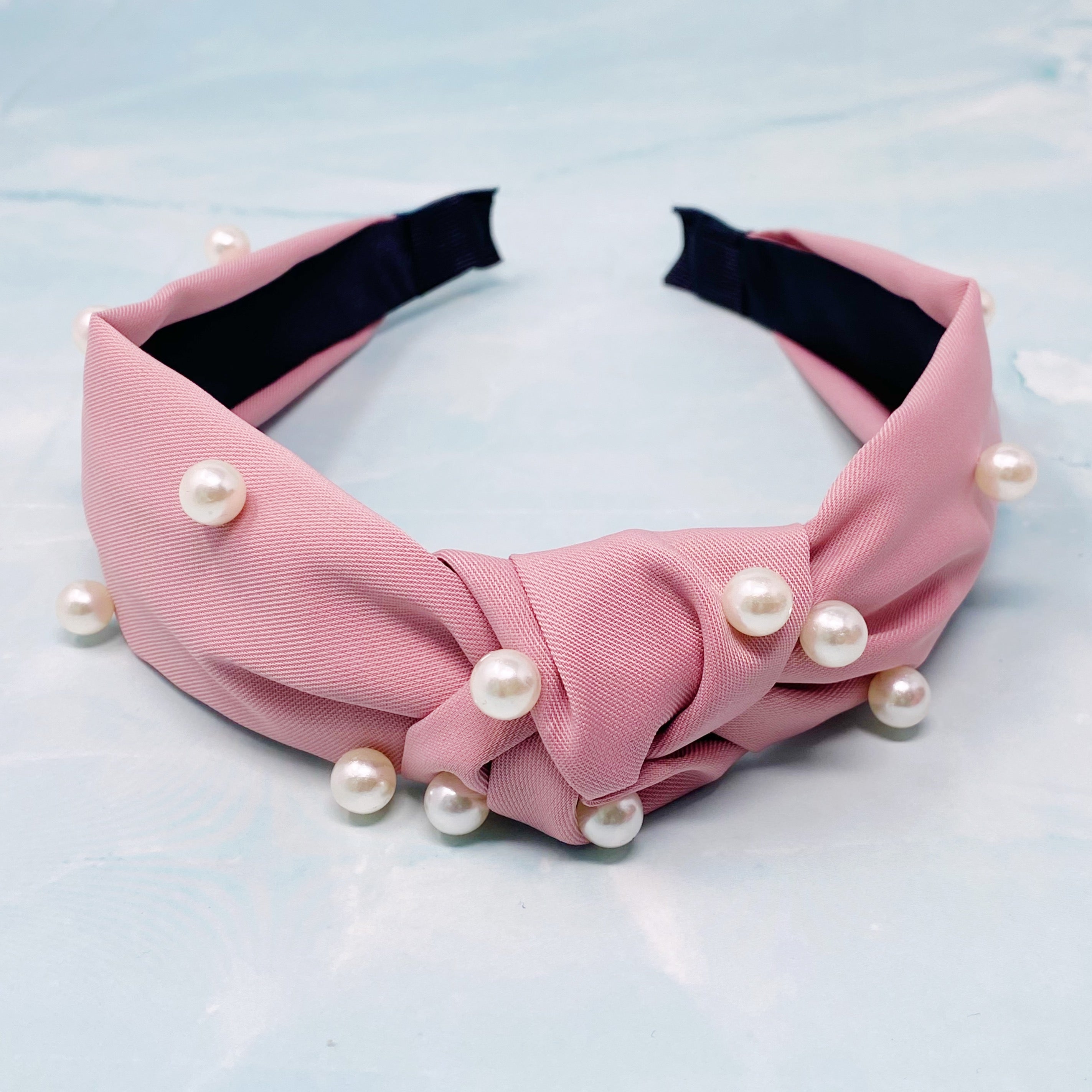 A stylish knotted headband adorned with pearls, perfect for enhancing any outfit.