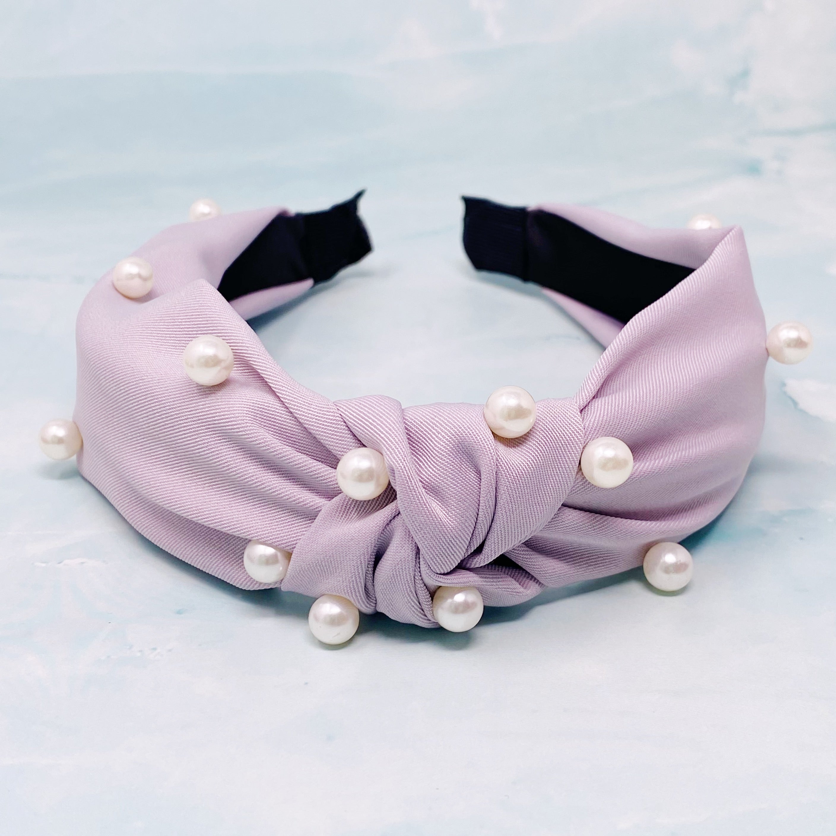 A stylish knotted headband adorned with pearls, perfect for enhancing any outfit.