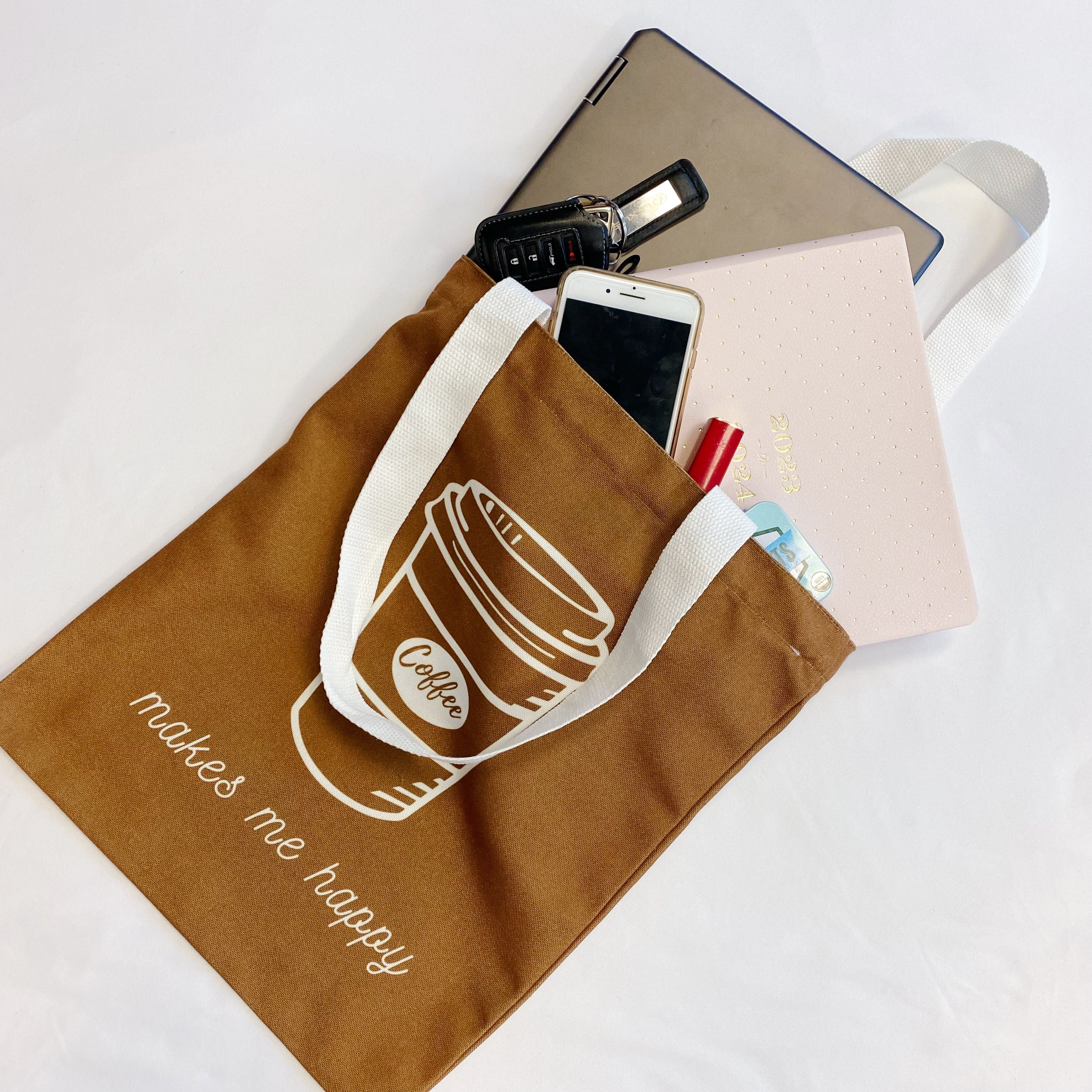 A stylish My Happy Canvas Tote featuring a positive graphic print, perfect for carrying books and small devices.