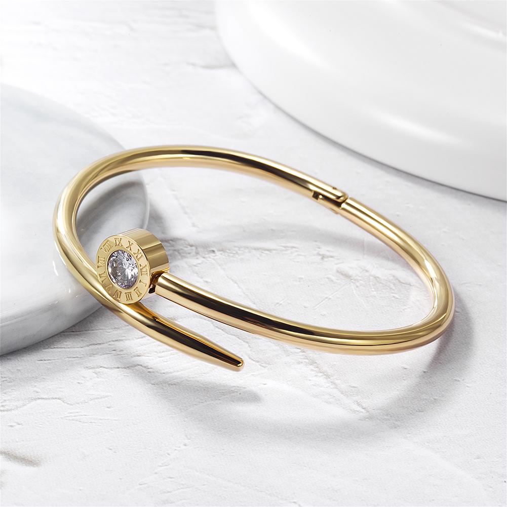 Elegant Nail Crossover Bangle made of stainless steel with gold plating, showcasing a modern design.