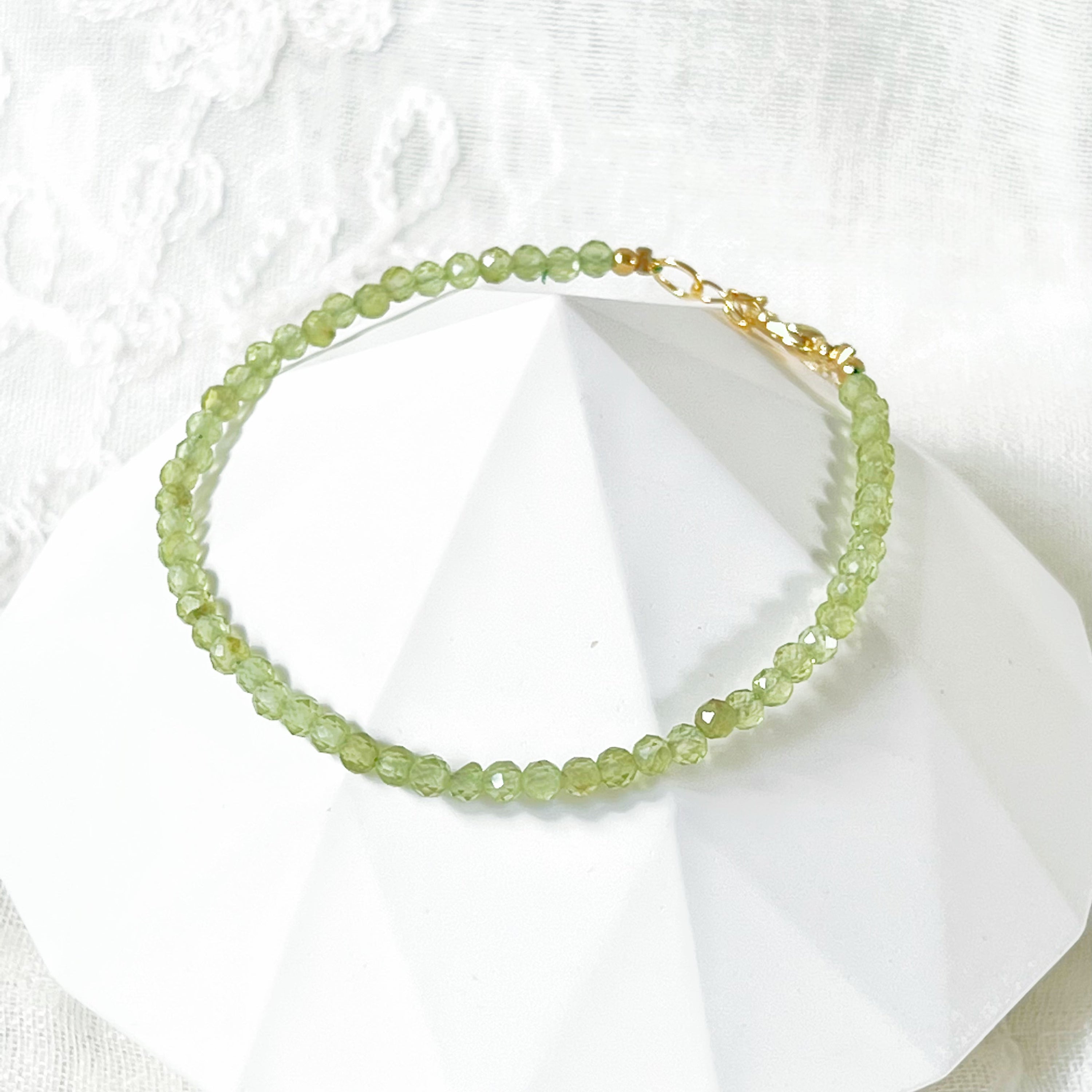 Natural Green Peridot Beaded Bracelet featuring 2-3mm peridot beads with gold plated bronze buckle and chain, elegantly displayed in a gift box.