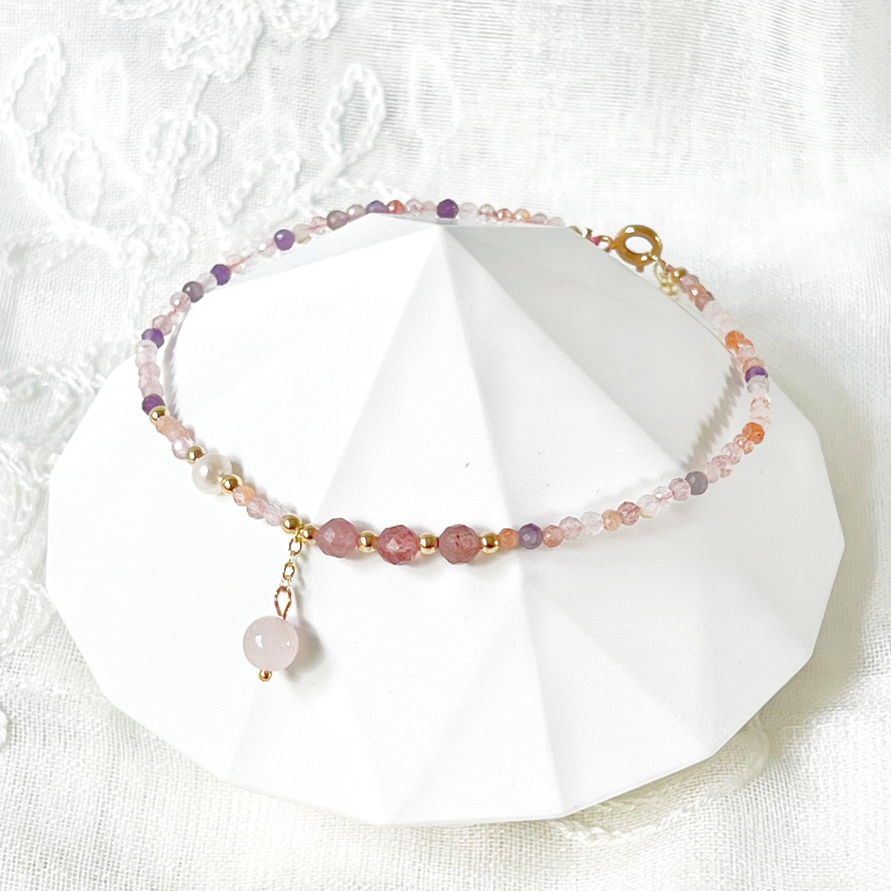 Natural rose quartz and amethyst beaded ankle bracelet with gold-tone accents, showcasing unique crystal patterns.