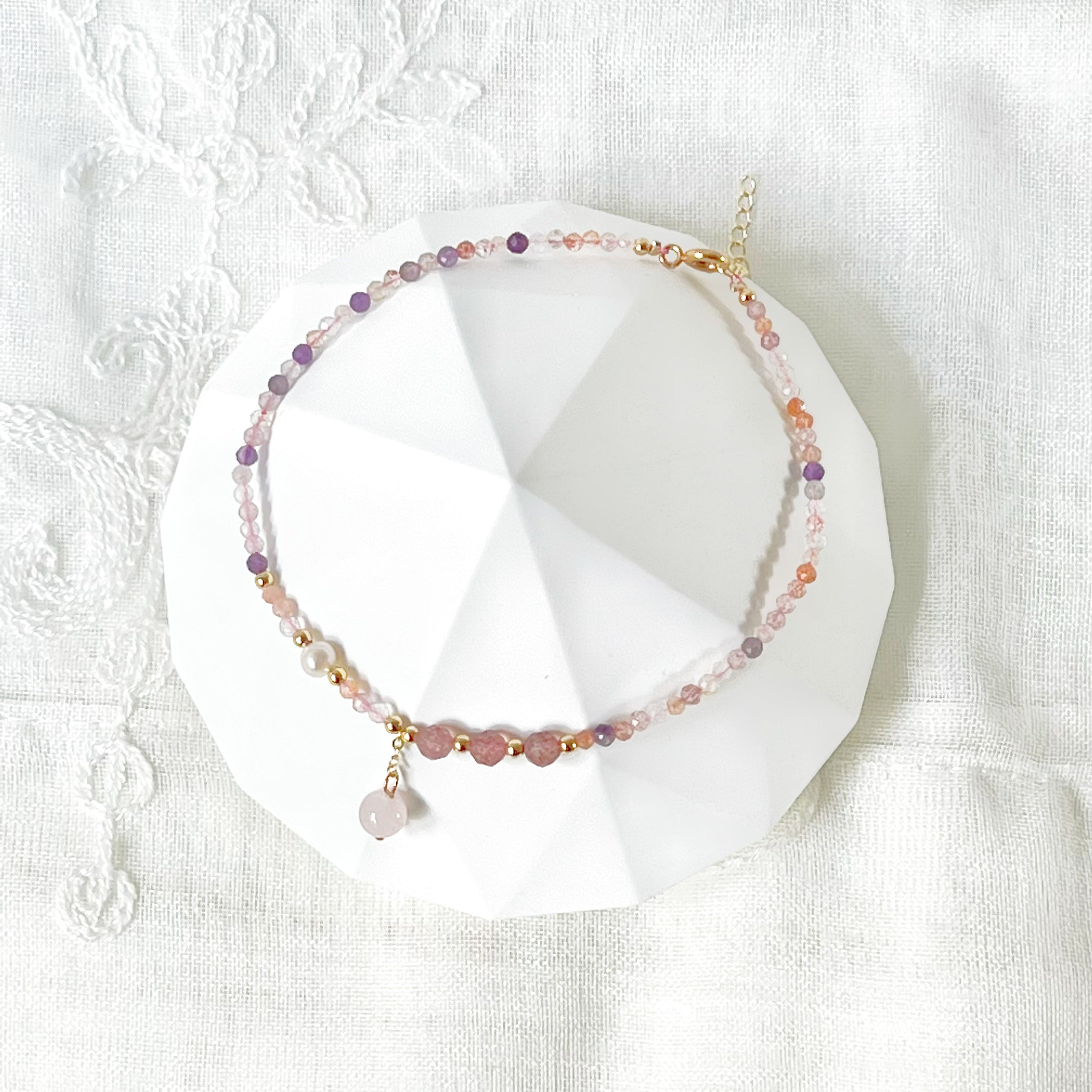 Natural rose quartz and amethyst beaded ankle bracelet with gold-tone accents, showcasing unique crystal patterns.