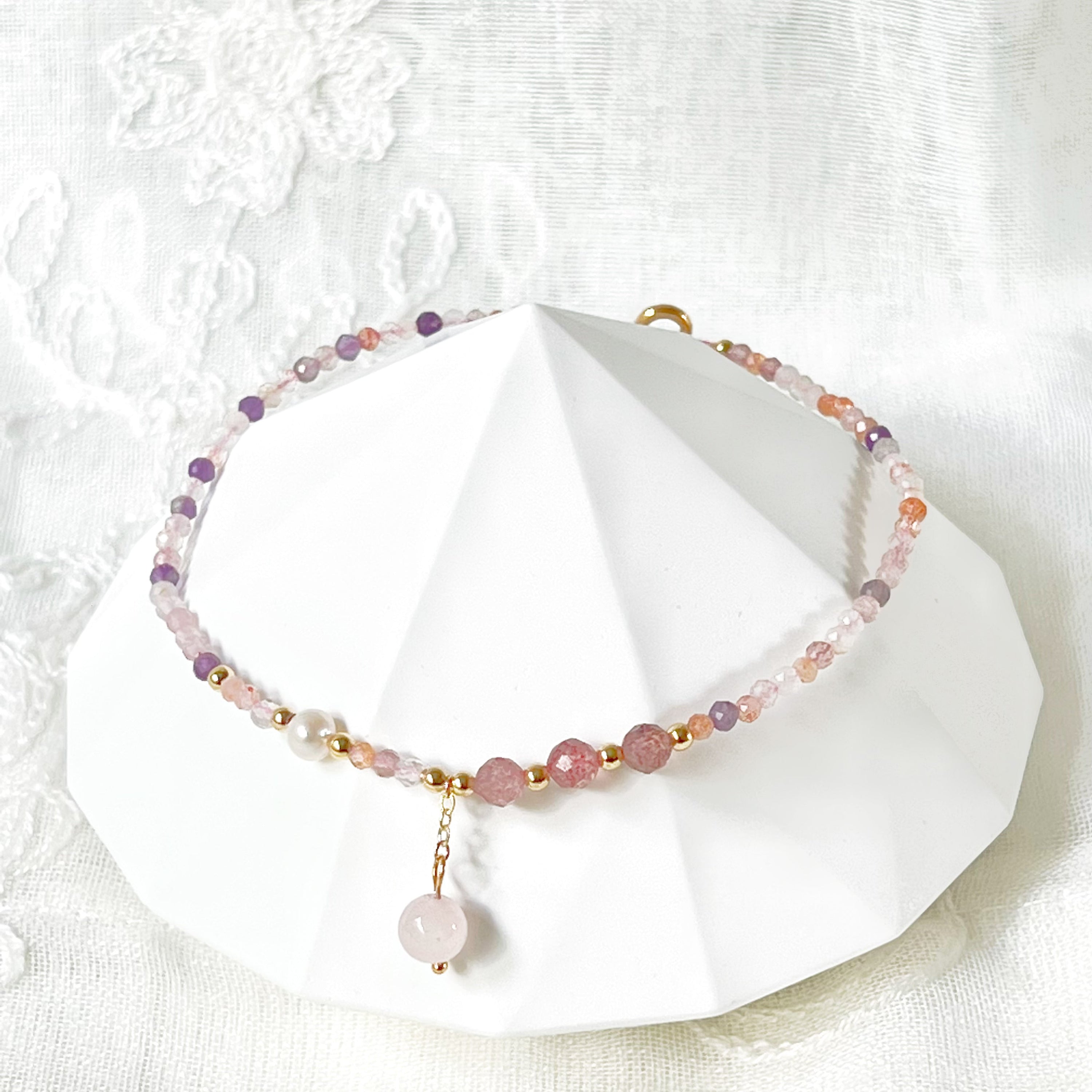 Natural rose quartz and amethyst beaded ankle bracelet with gold-tone accents, showcasing unique crystal patterns.