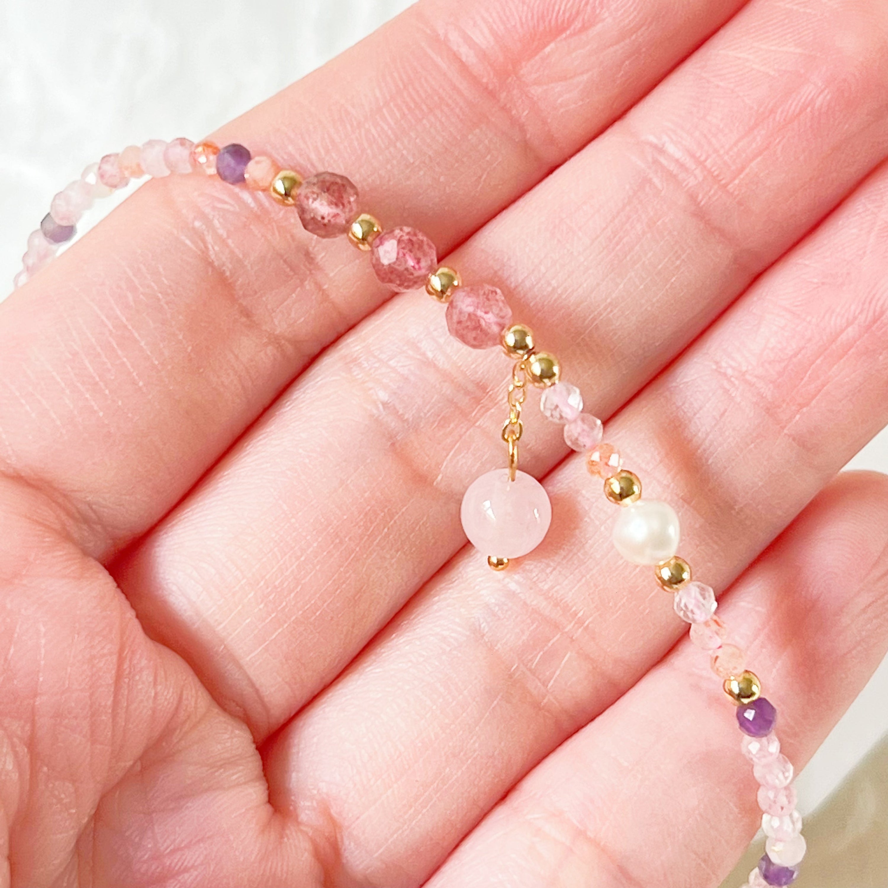 Natural rose quartz and amethyst beaded ankle bracelet with gold-tone accents, showcasing unique crystal patterns.