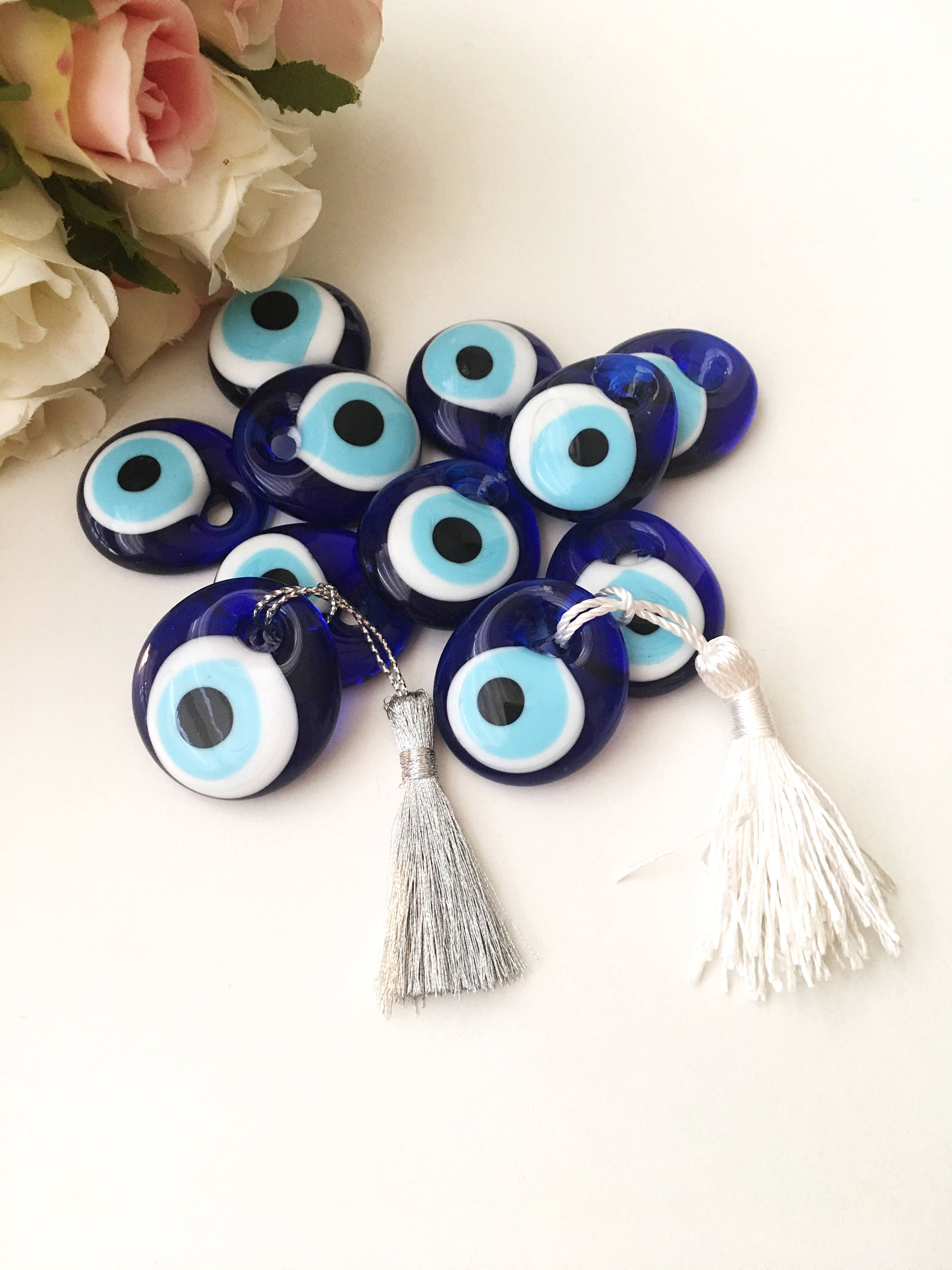 A collection of 50 blue glass evil eye beads with tassels, symbolizing protection and good luck, perfect for wedding favors.