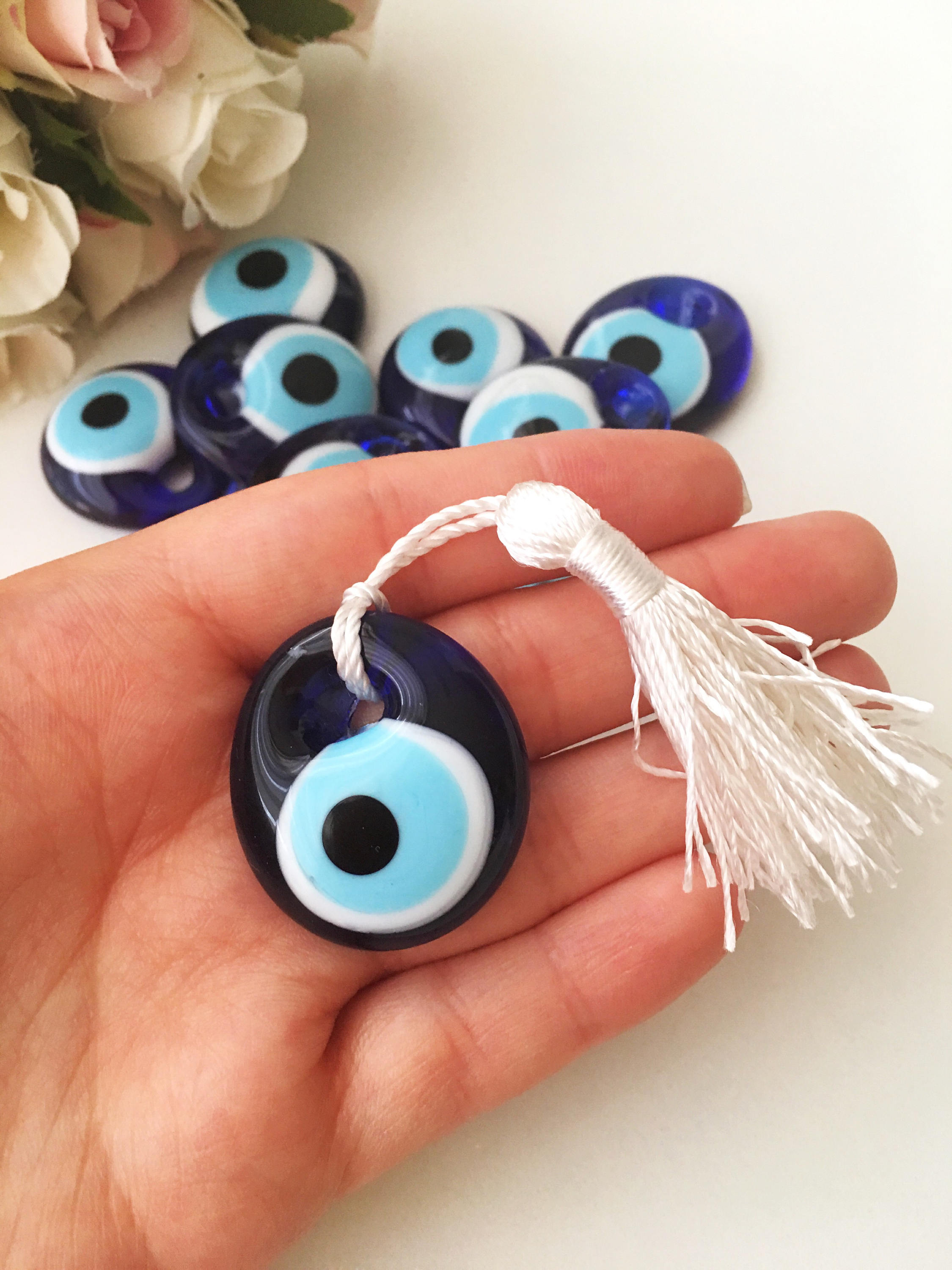 A collection of 50 blue glass evil eye beads with tassels, symbolizing protection and good luck, perfect for wedding favors.